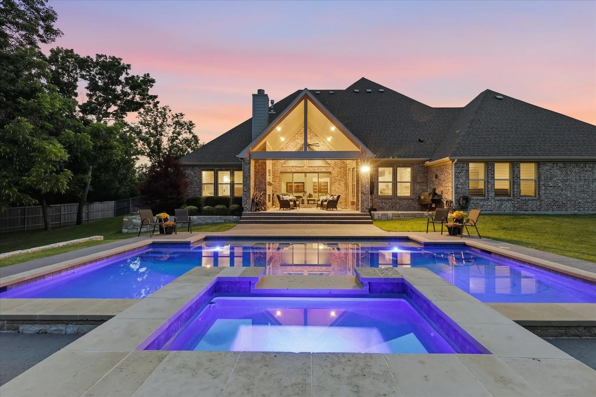 Expansive backyard featuring a multi-level pool with integrated spa, stone coping, and a covered outdoor living area