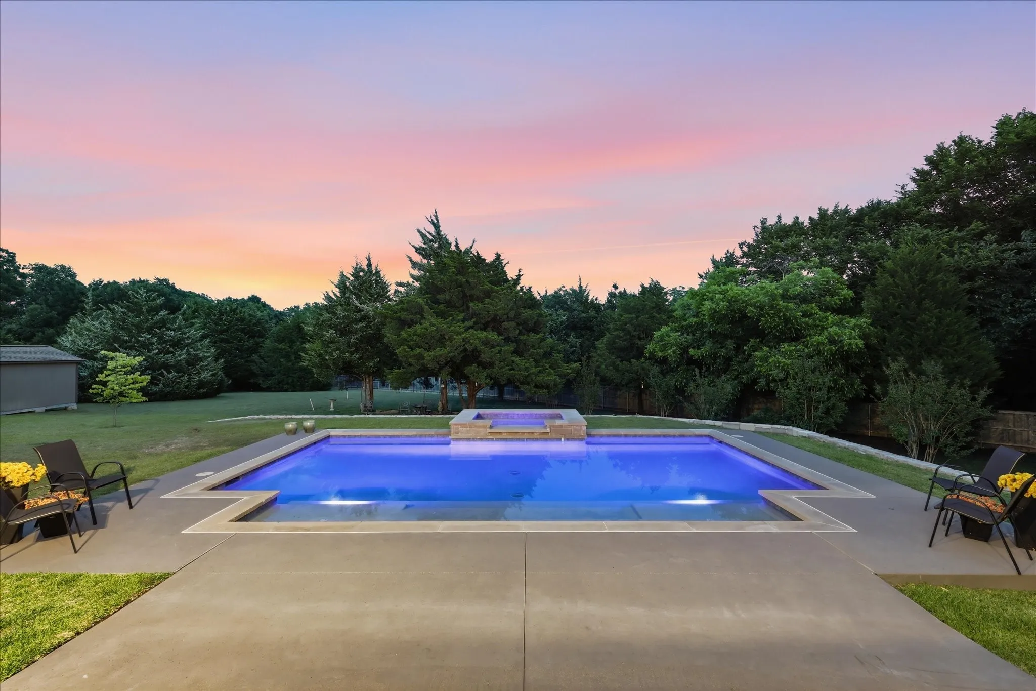 Rectangular swimming pool with integrated spa and surrounding concrete patio
