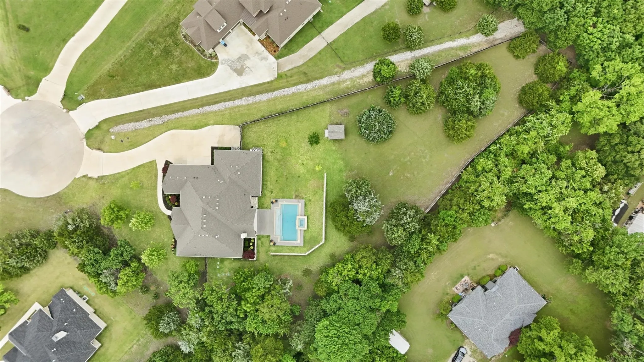 Property featuring a large residential structure, an in-ground swimming pool, and extensive surrounding greenery