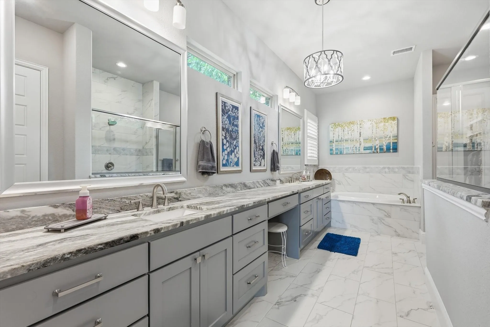 Dual vanity with stone countertops and undermount sinks, built-in soaking tub with tile surround, glass-enclosed shower, and tile flooring