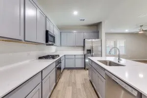 Kitchen featuring grey cabinetry, white countertops, stainless steel appliances, wood-finish flooring, and recessed lighting