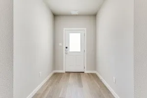 Wood-finish flooring with light-toned walls and trim, featuring a white door with an upper glass panel