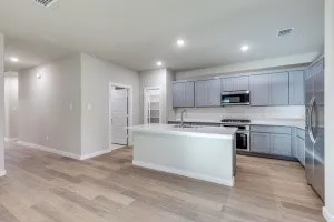 Modern kitchen featuring an island, light gray cabinetry, stainless steel appliances, and wood-finish flooring