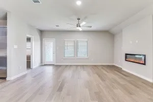 Wood-finish flooring, recessed lighting, ceiling fan, contemporary wall-mounted electric fireplace, and a full-light door