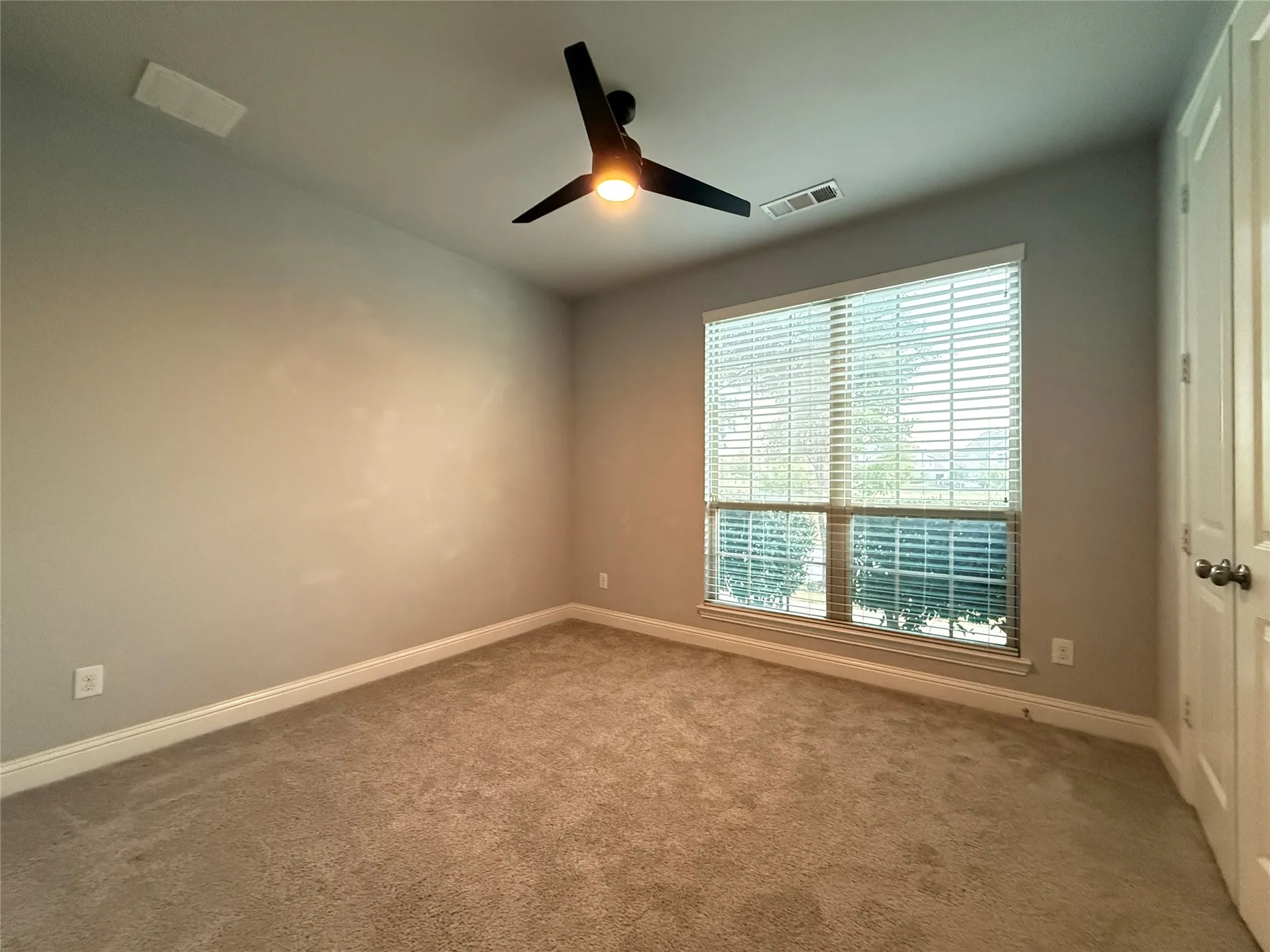Neutral wall color, plush carpet flooring, ceiling fan with integrated lighting, window with blinds, and white trim