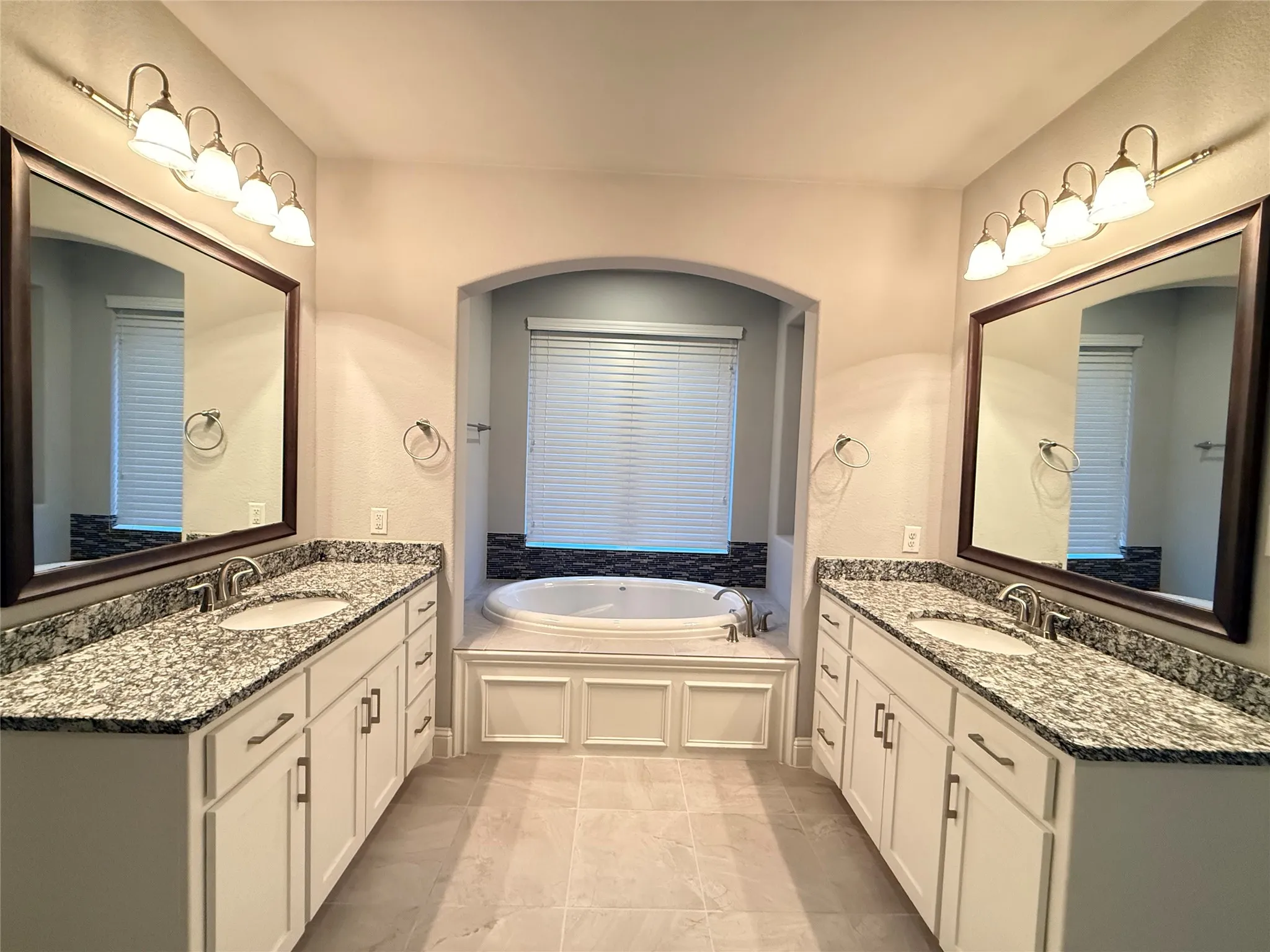 Dual vanities with granite countertops, undermount sinks, and framed mirrors