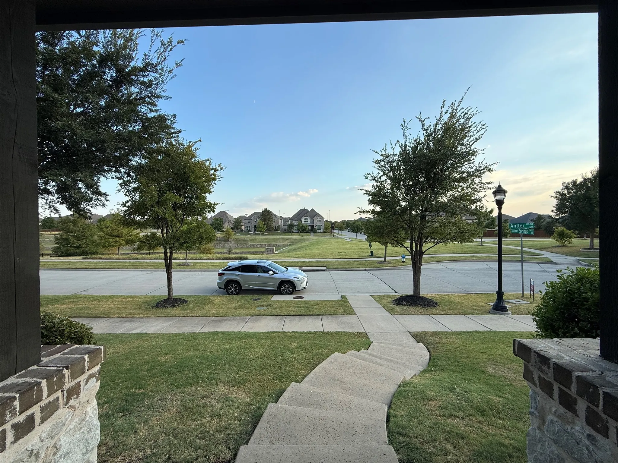 Brick and stone exterior detailing, concrete walkway, established front yard landscaping, street light fixture, paved street access