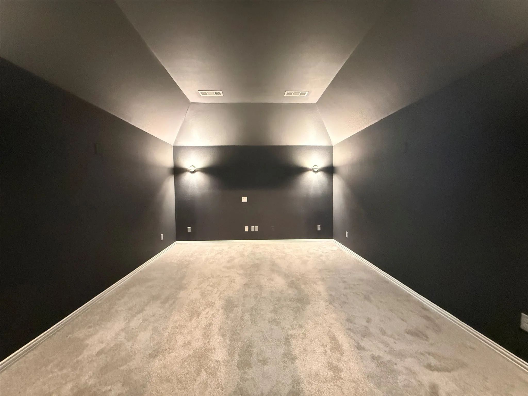 Recessed ceiling, angled ceiling design, wall sconce lighting, dark wall finish, and neutral-toned carpeting