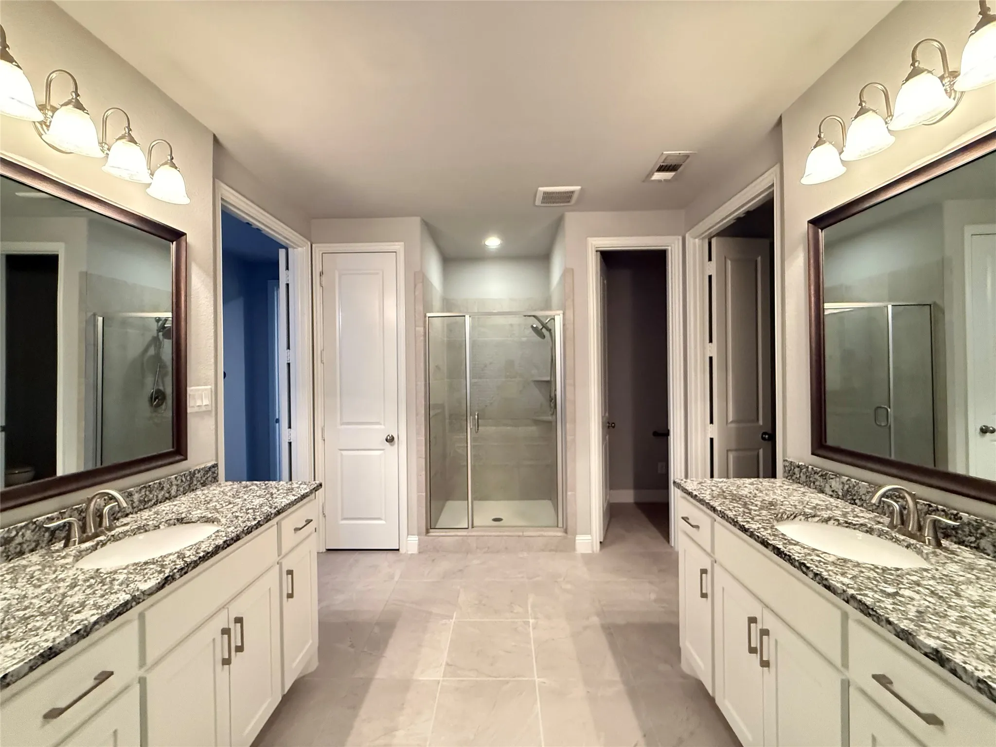 Dual white vanities with granite countertops, undermount sinks, and chrome fixtures
