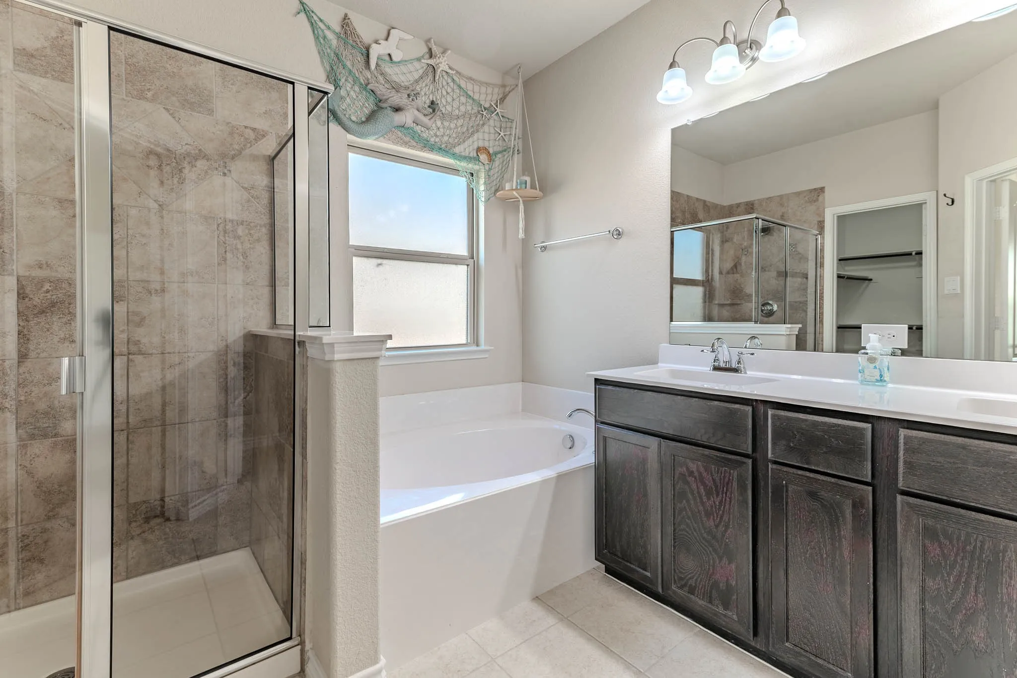 Bathroom with independent shower and bath, vanity, dual sinks and tile patterned floors