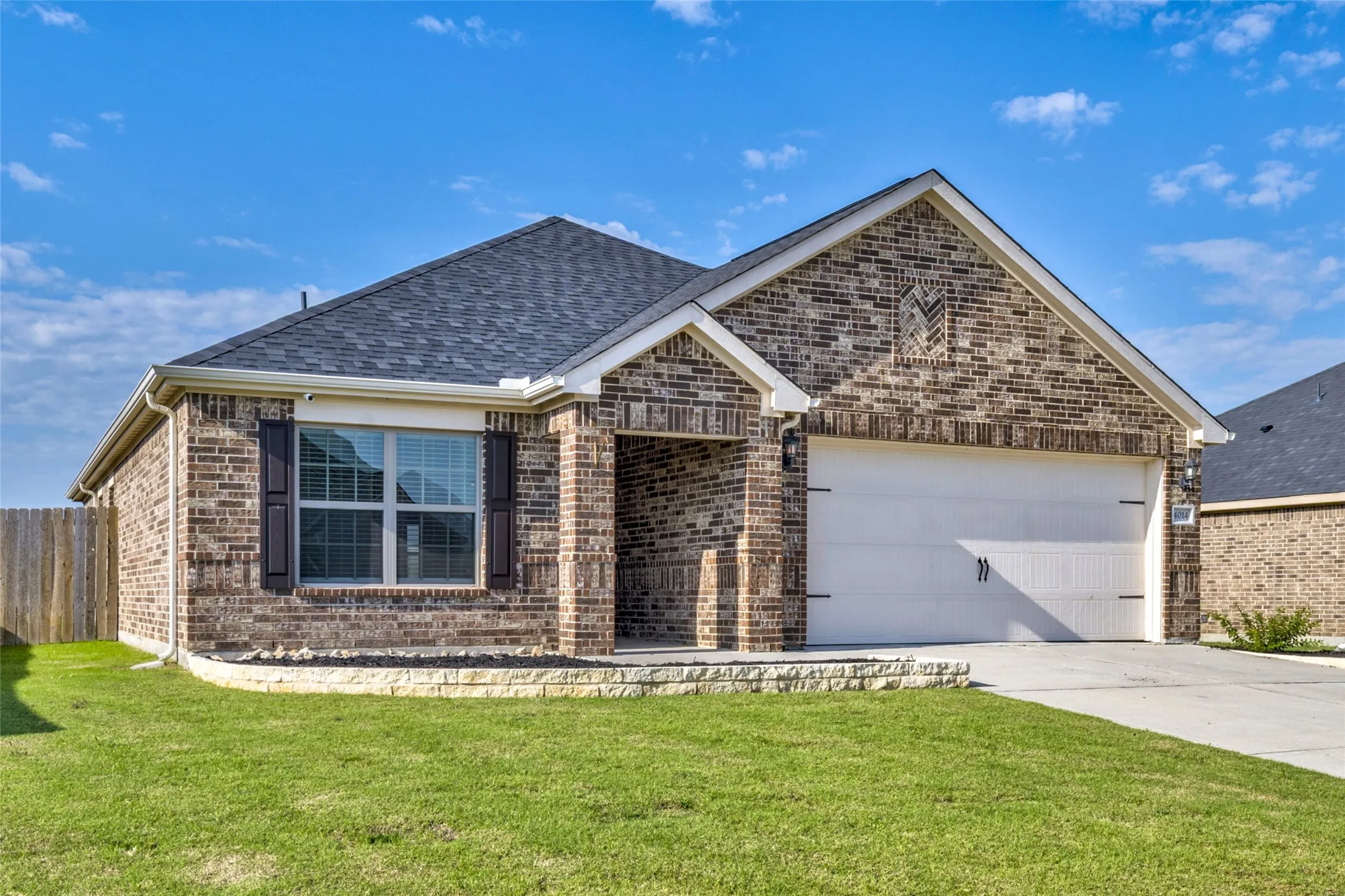 Brick exterior with white trim, a dark shingle roof, a two-car garage, and a concrete driveway