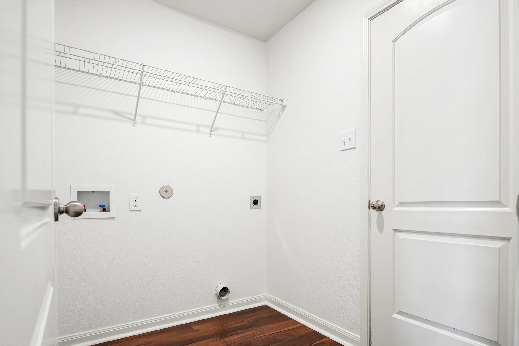 Dedicated utility area with wood-finish LVP  flooring and a wire storage shelf