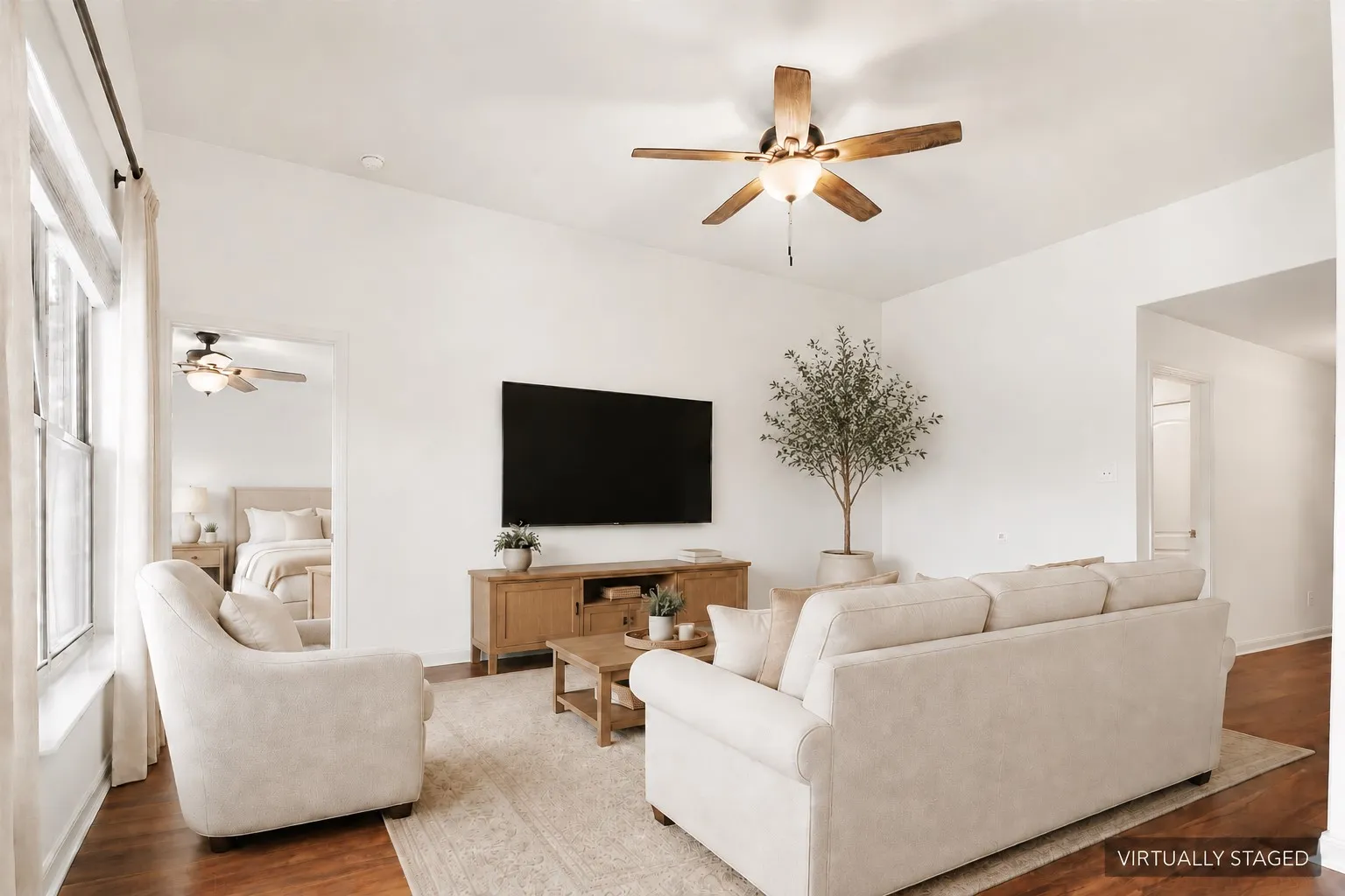 Virtually Staged. Vaulted ceiling with a wood-finish ceiling fan, wood-finish  LVP flooring, and white walls