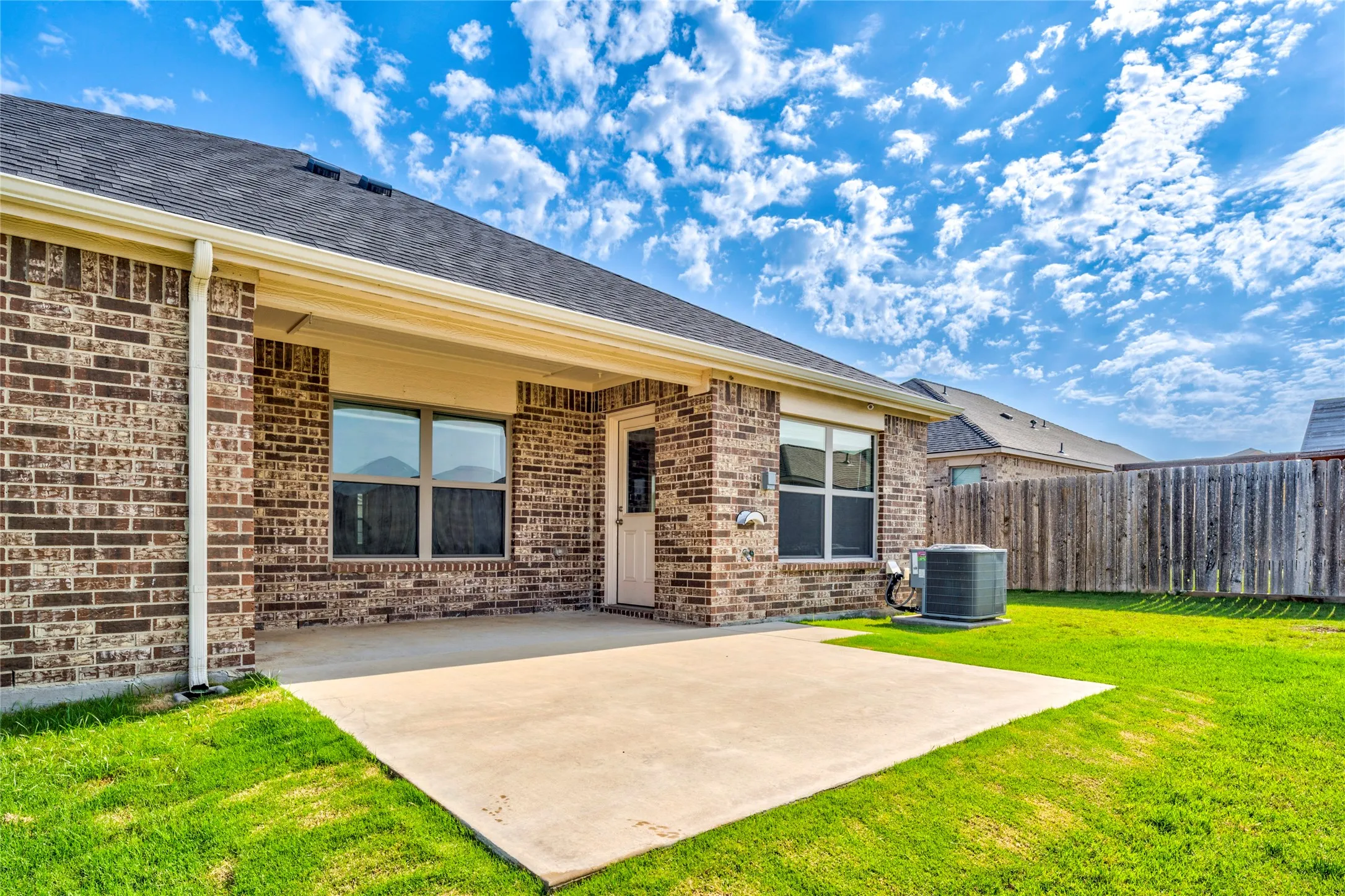 Back patio area, full brick exterior with a covered patio, concrete slab, and nice sized yard.