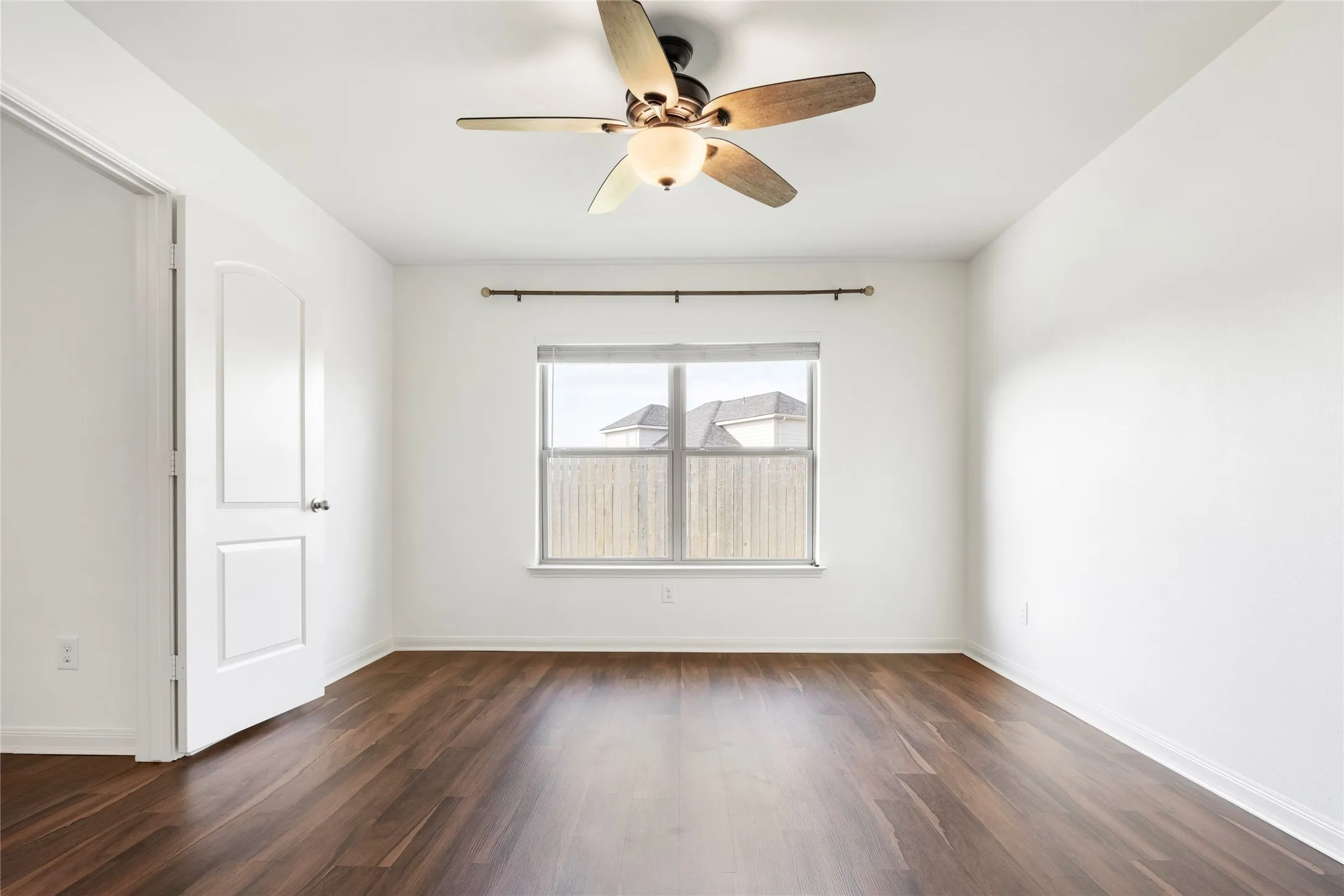 Wood-finish LVP  flooring with a ceiling fan light fixture. View from the primary bathroom entrance.