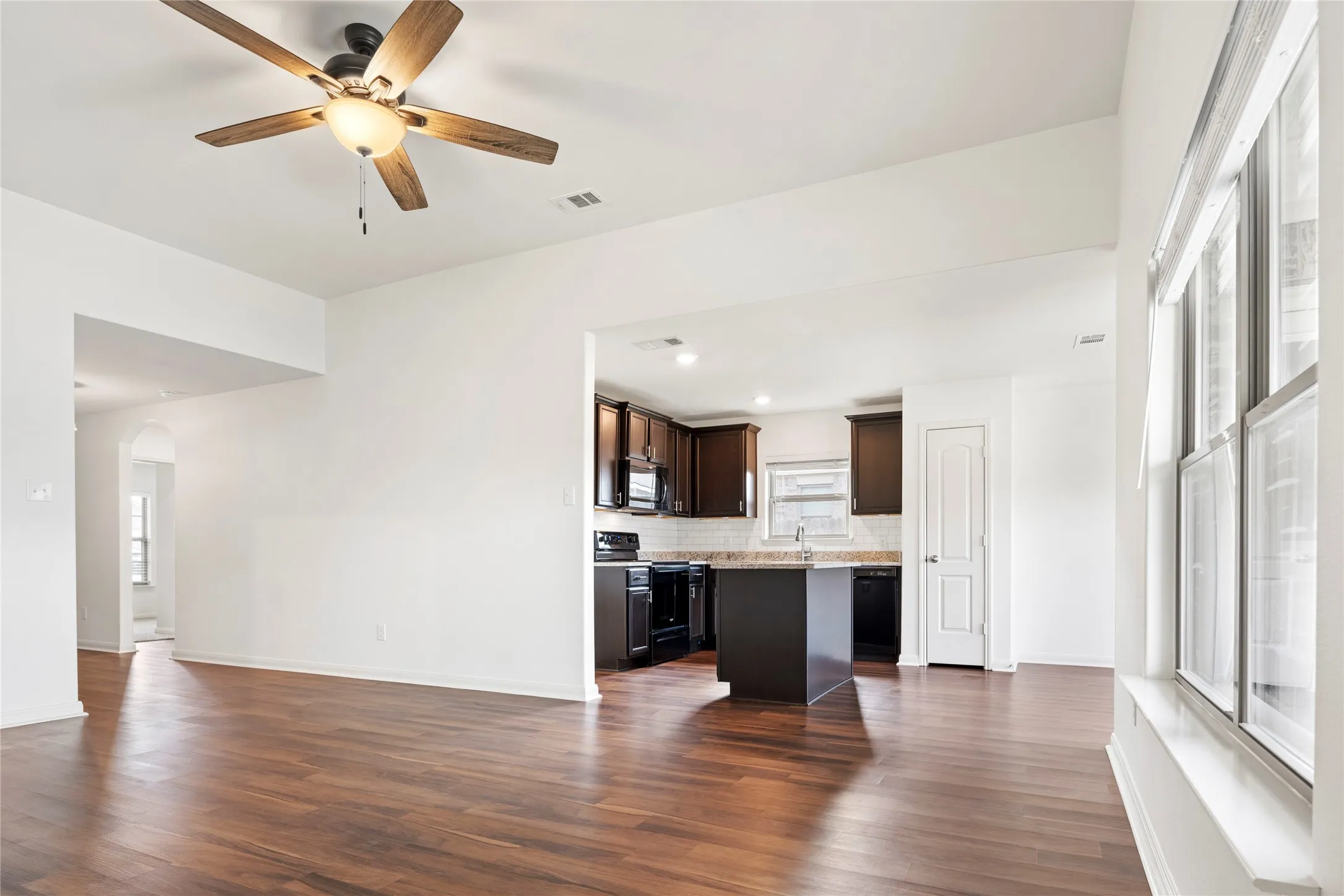 Wood-finish LVP  flooring throughout, with a ceiling fan featuring a light fixture. View from the Primary bedroom.