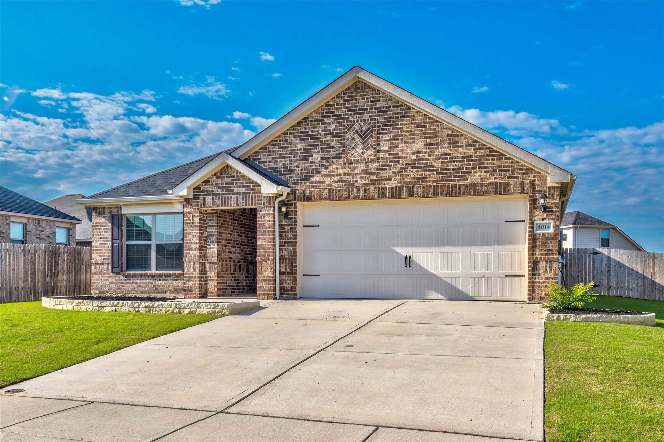 Full brick exterior with an attached two-car garage, covered entry, and front yard.