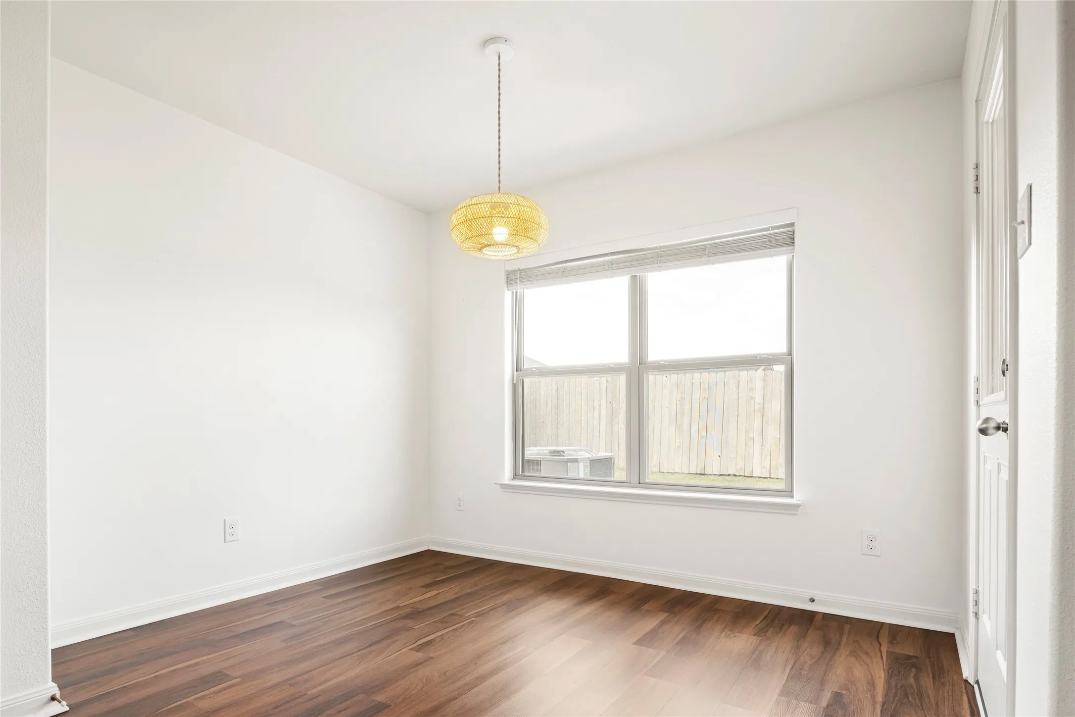 Wood-finish LVP flooring, white walls, and a contemporary pendant light fixture