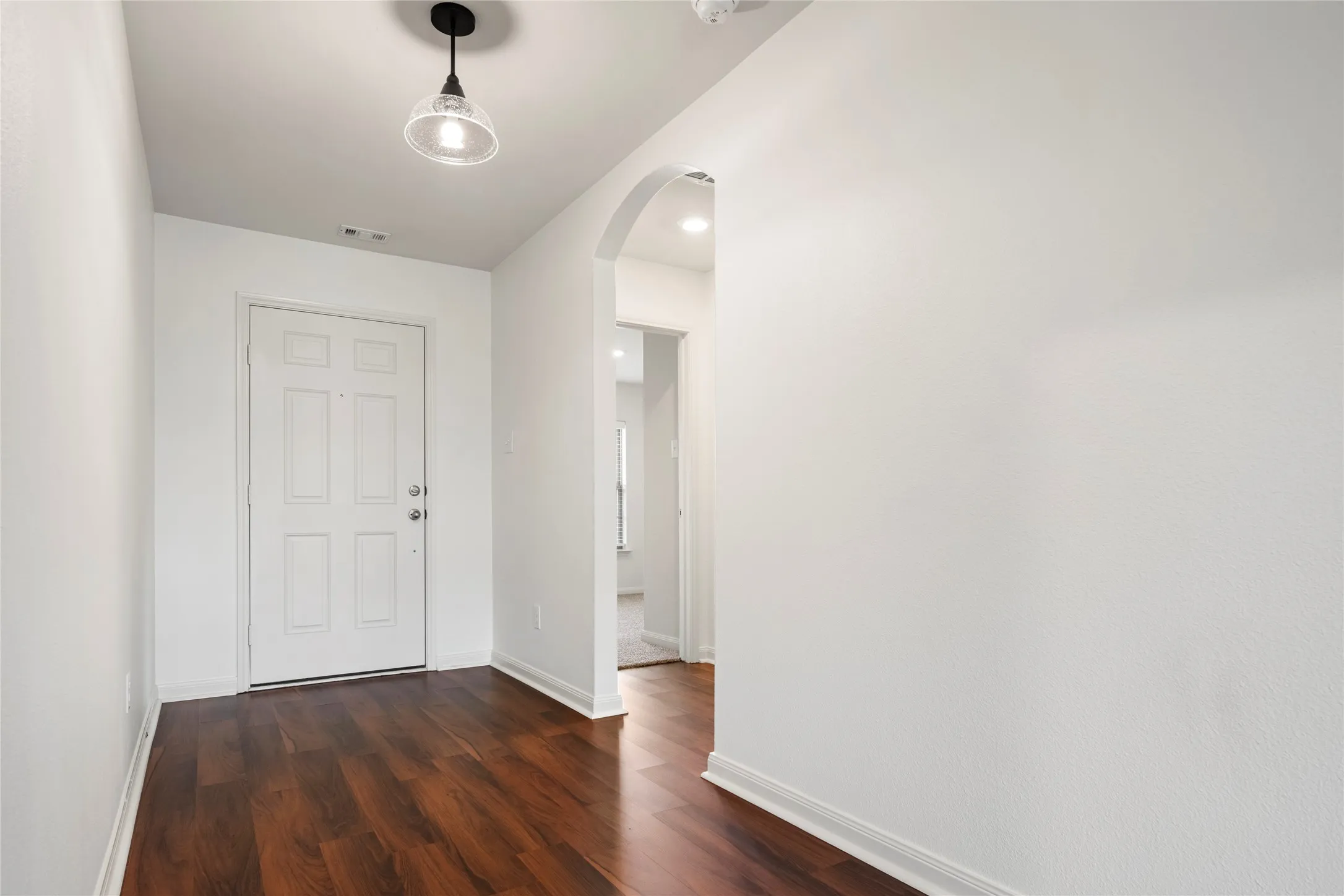 Entryway featuring wood-finish LVP  flooring, white walls, and an arched doorway