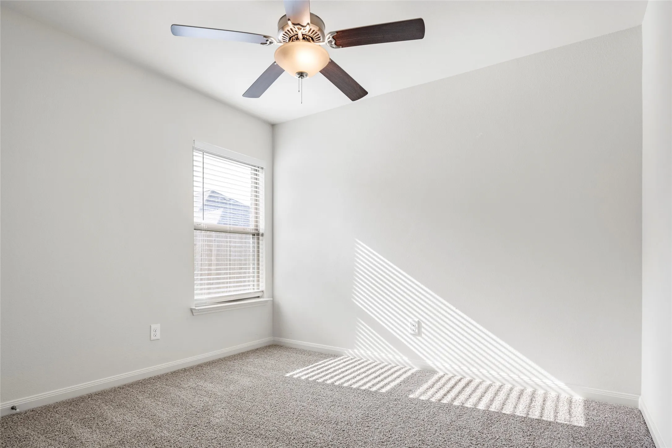 Secondary bedroom. Carpeted room featuring a single window with blinds and a ceiling fan with integrated lighting