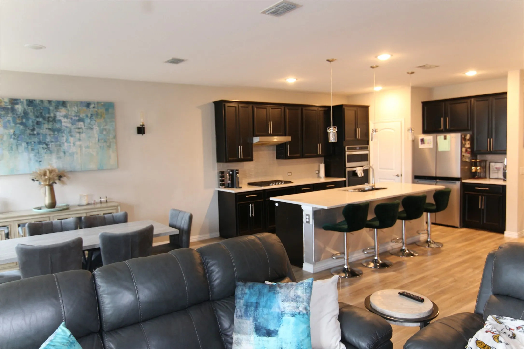 Spacious kitchen featuring dark cabinetry, stainless steel appliances, a large island with seating, and recessed lighting