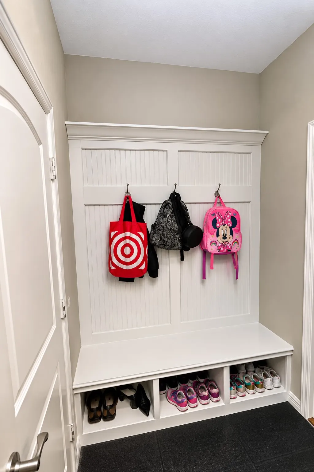 Built-in white storage bench with open shelving, beadboard backing, and integrated hooks