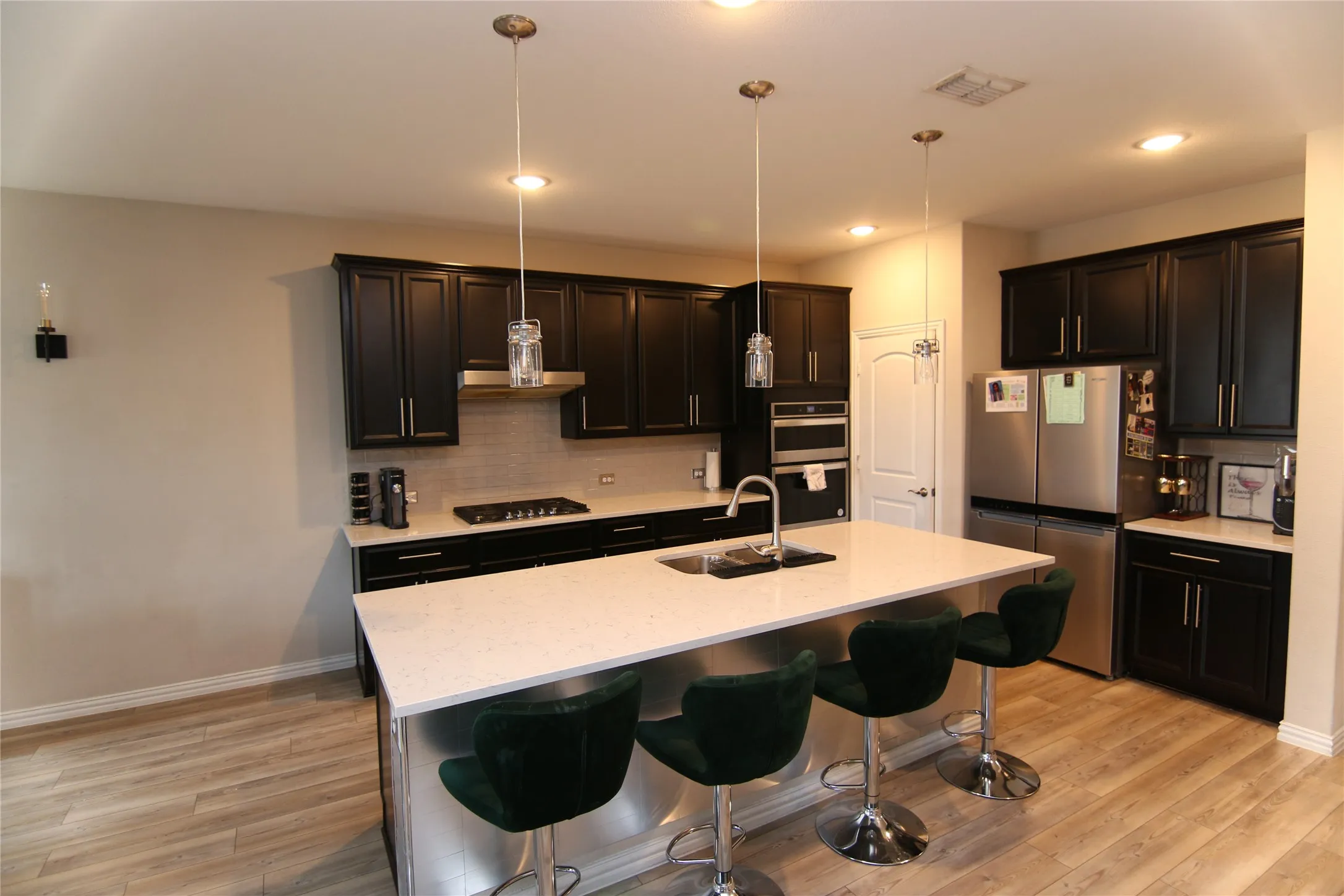 Kitchen featuring dark wood cabinetry, light-colored countertops, stainless steel appliances, and wood-finish flooring