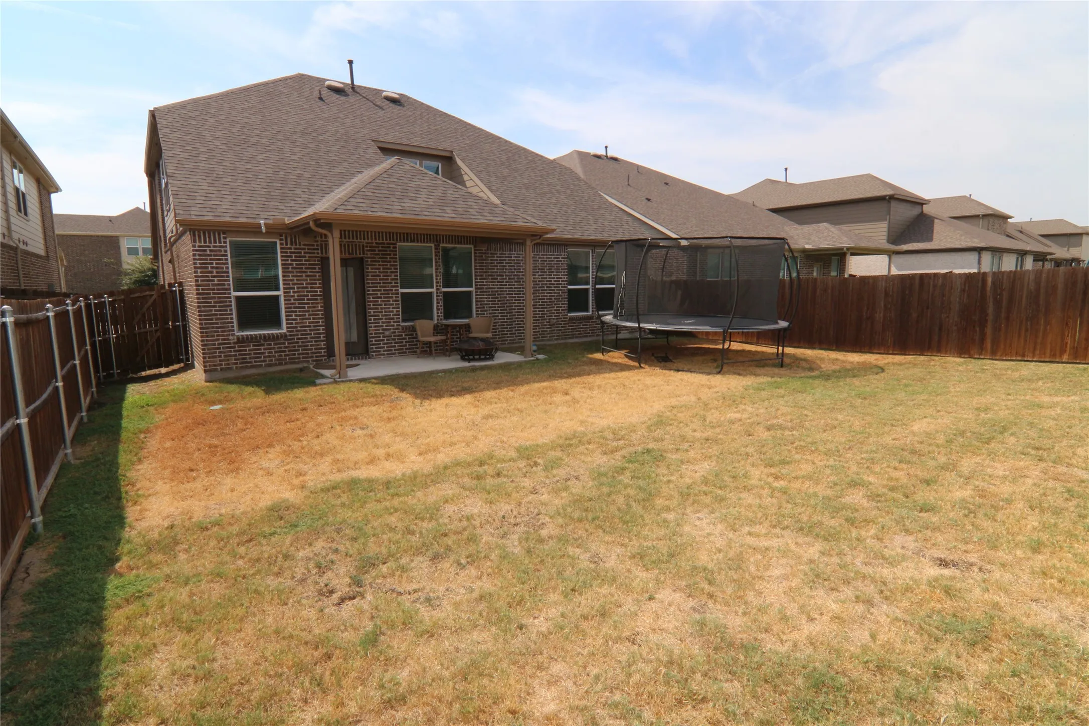Brick exterior with a covered patio, concrete slab, and private fenced yard