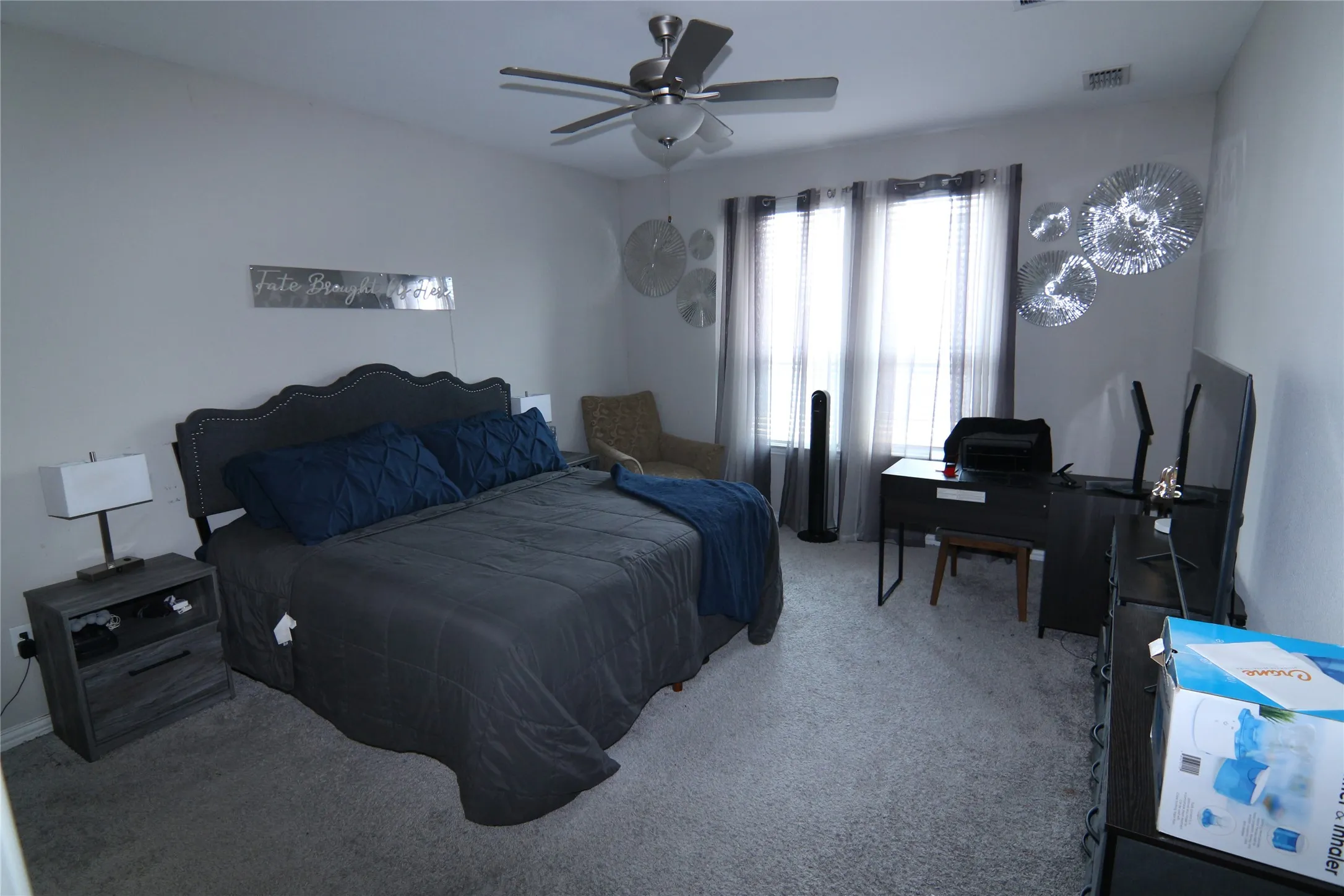 Neutral wall tones, gray carpeting, and a ceiling fan with integrated lighting