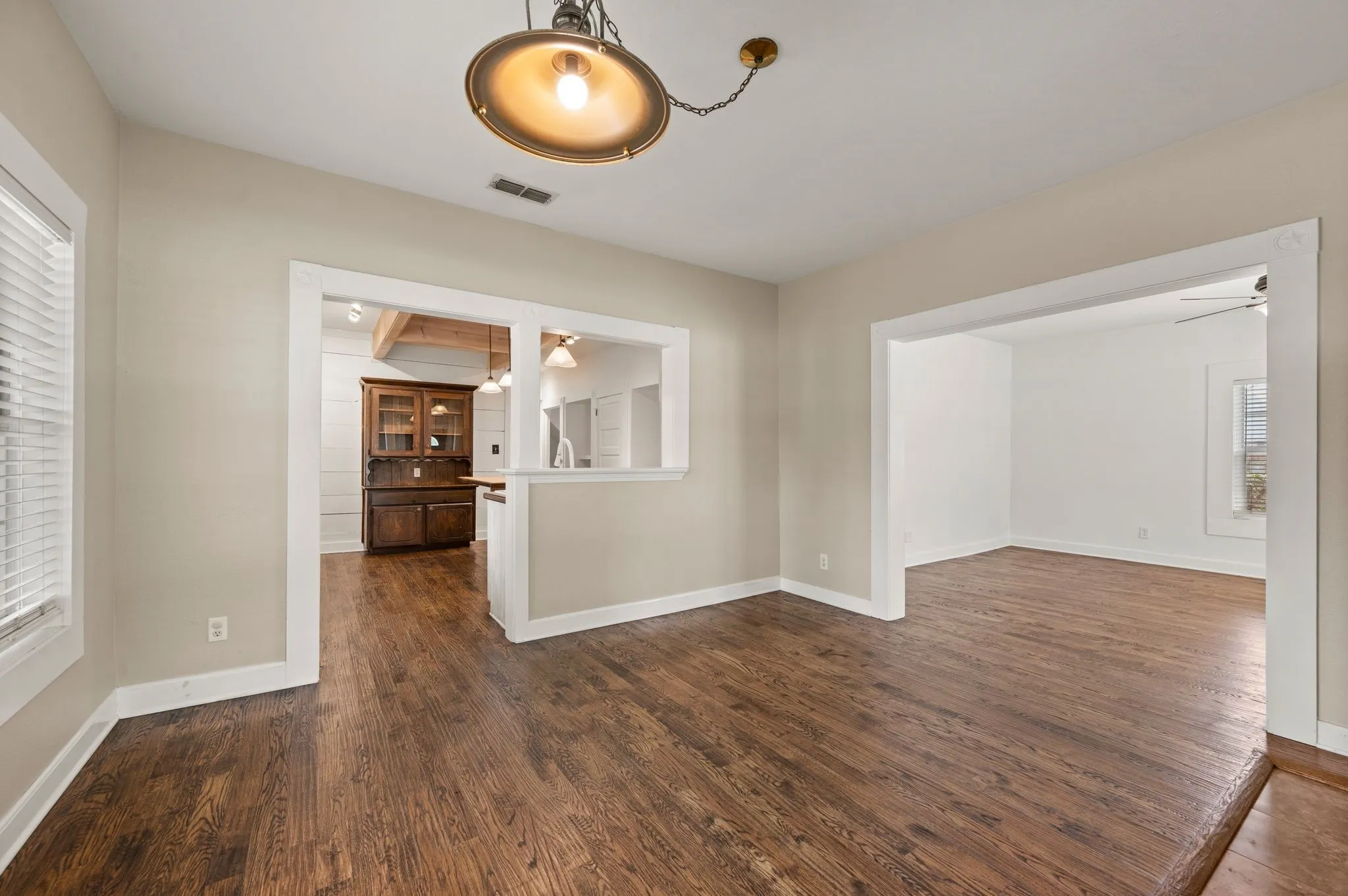 Unfurnished room featuring dark wood-style floors, baseboards, ceiling fan, and visible vents