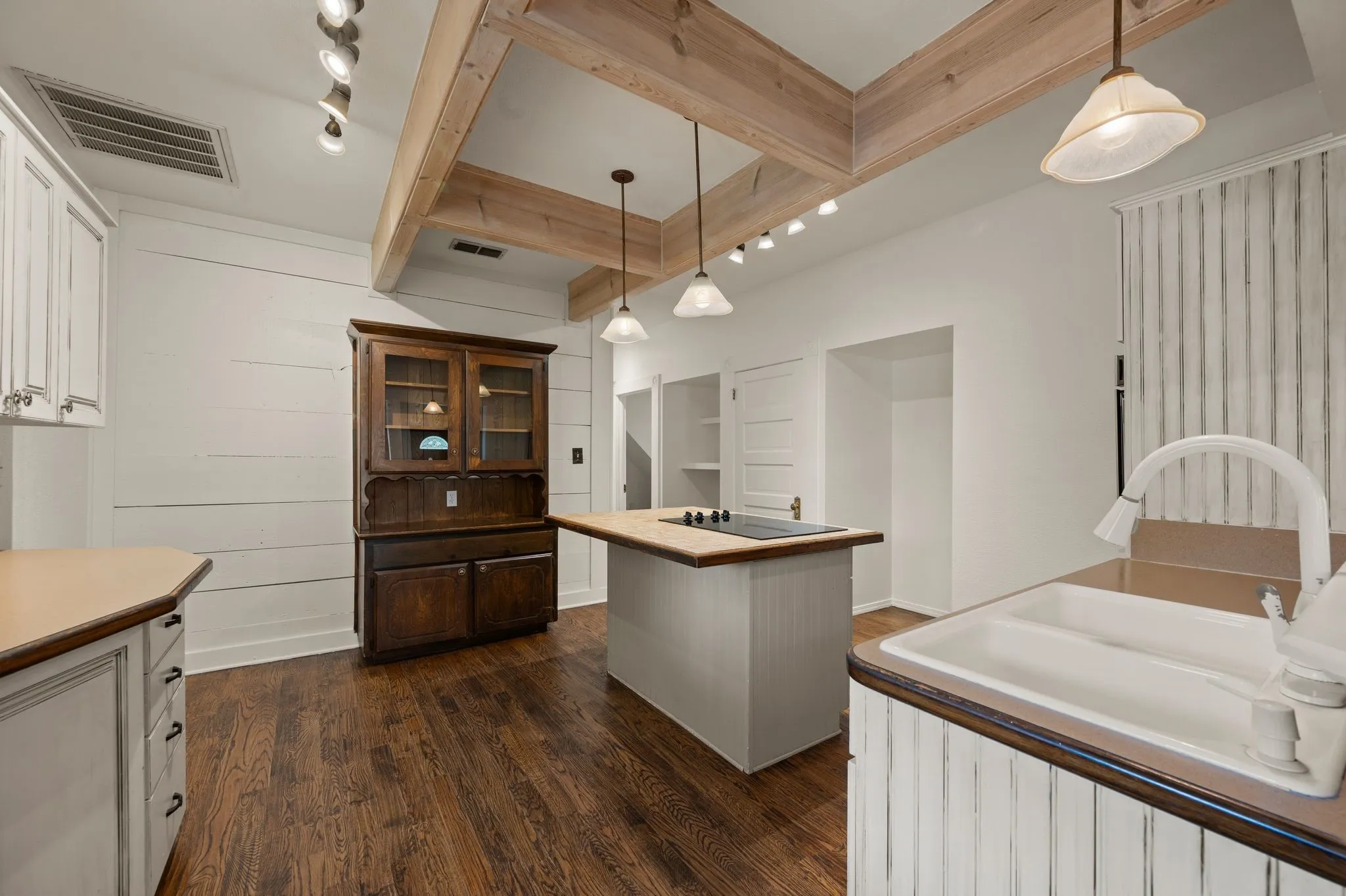 Kitchen featuring dark wood-type flooring, a sink, visible vents, and beam ceiling