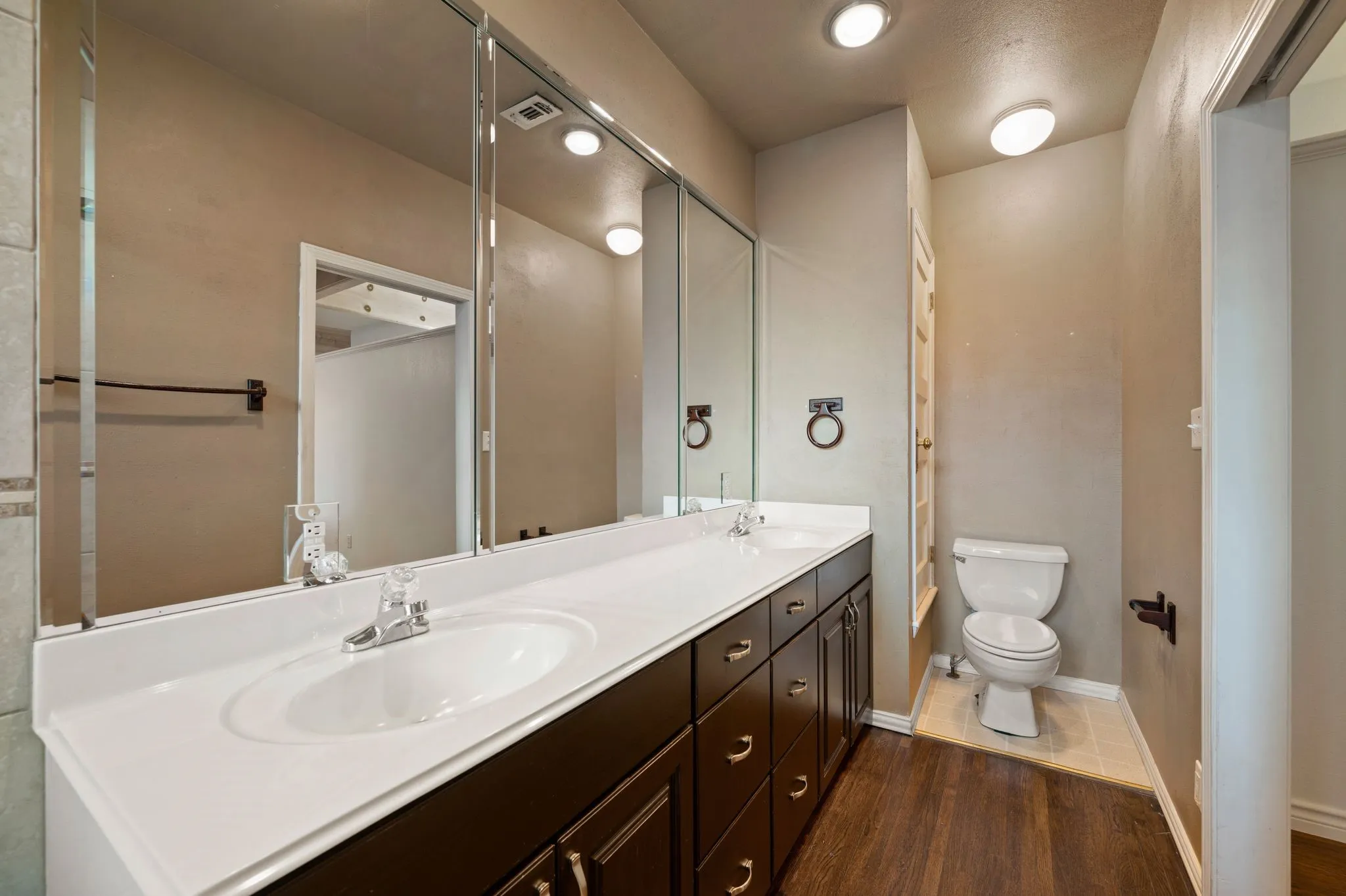 Full bath with toilet, wood finished floors, a sink, and visible vents