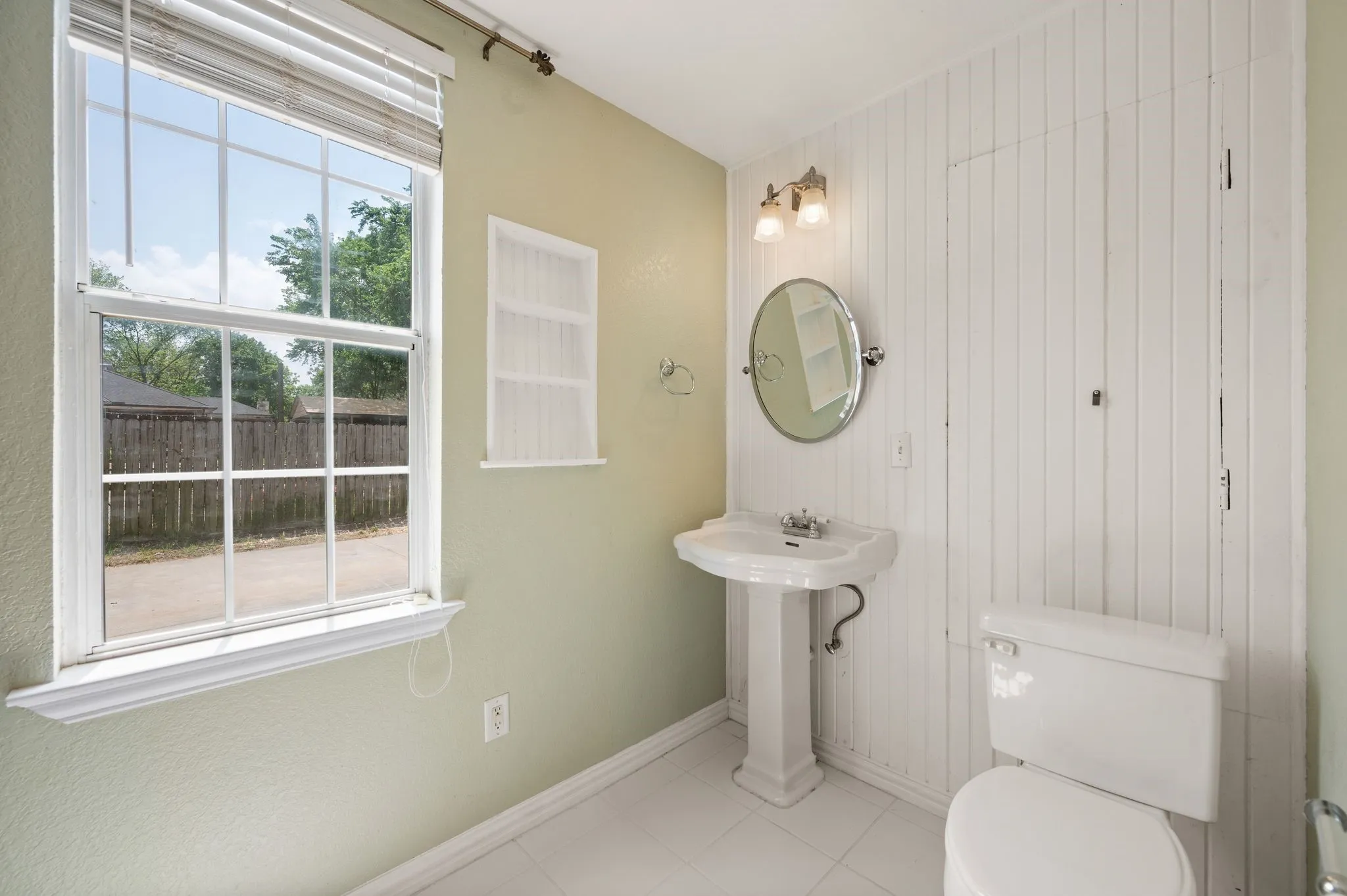Bathroom featuring wood walls, a sink, baseboards, toilet, and tile patterned flooring