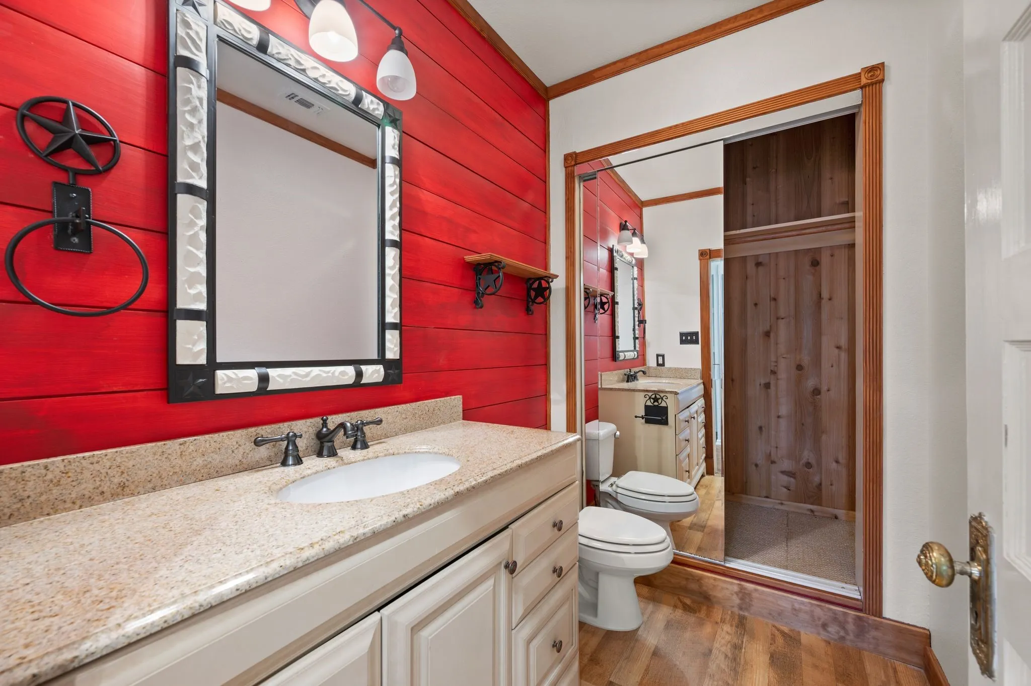 Bathroom with wood walls, wood finished floors, toilet, vanity, and ornamental molding