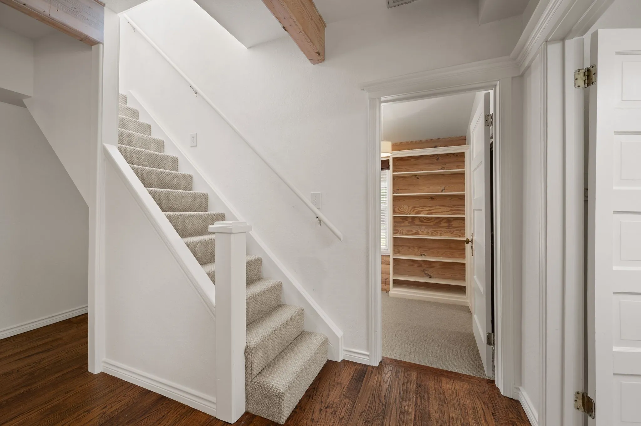 Stairway with beamed ceiling, wood finished floors, and baseboards