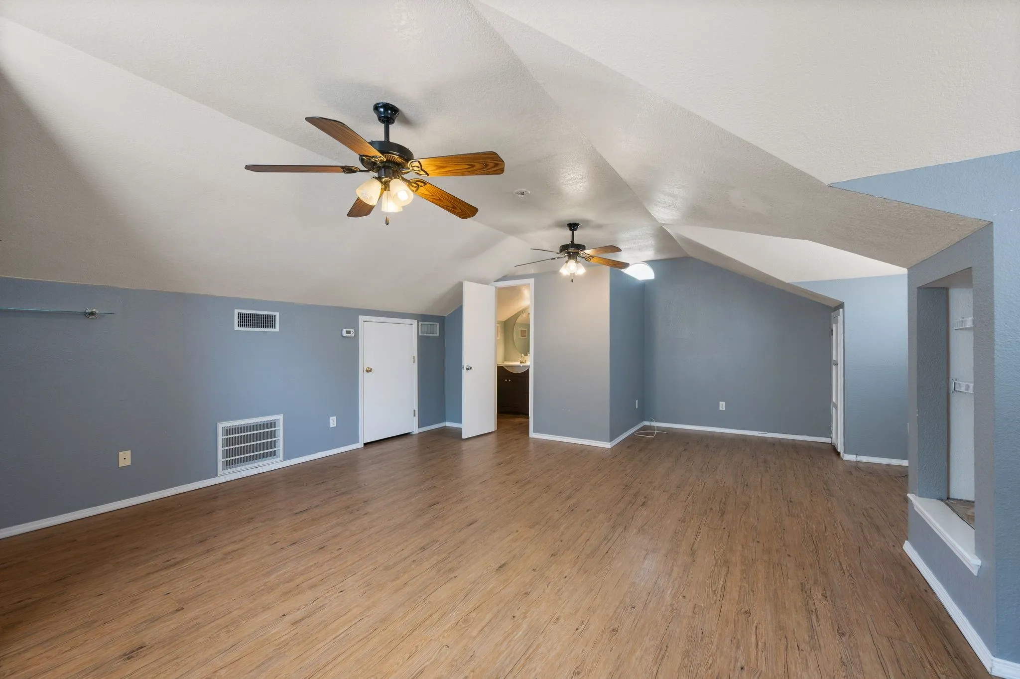 Bonus room with a ceiling fan, wood finished floors, and visible vents