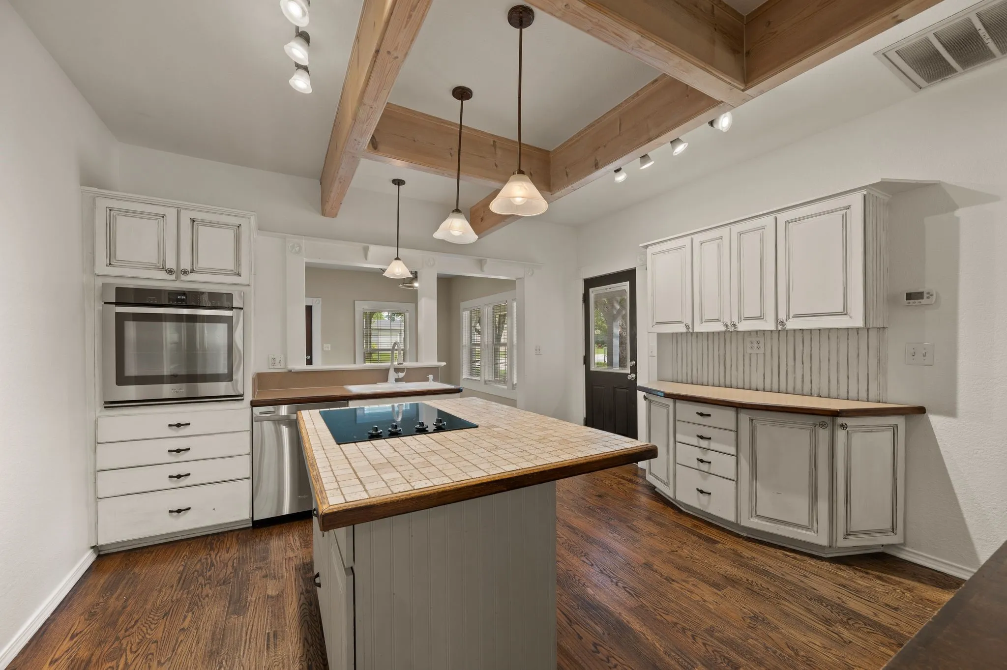 Kitchen with dark wood finished floors, stainless steel appliances, visible vents, beamed ceiling, and a kitchen island