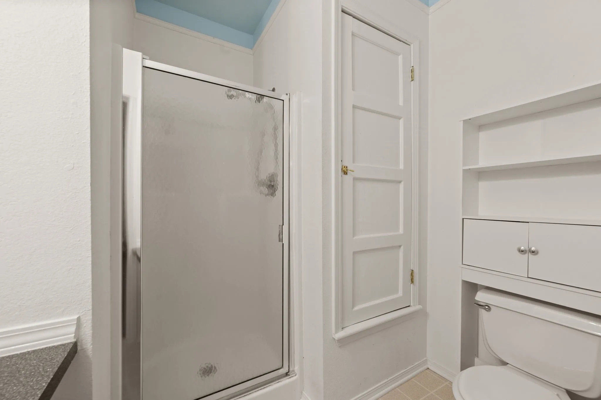 Bathroom with toilet, baseboards, and a stall shower