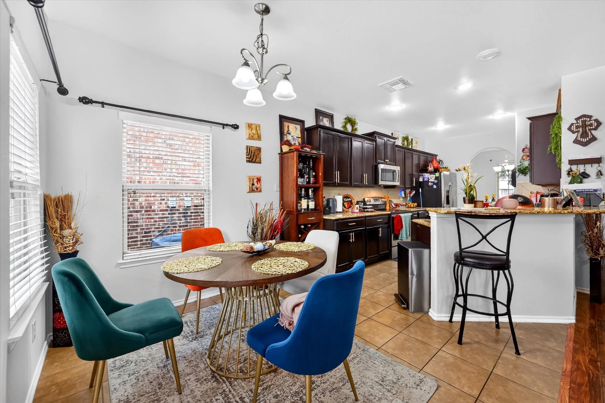 Kitchen featuring dark wood-finish cabinetry, tile flooring, recessed lighting, and a breakfast bar with a stone countertop