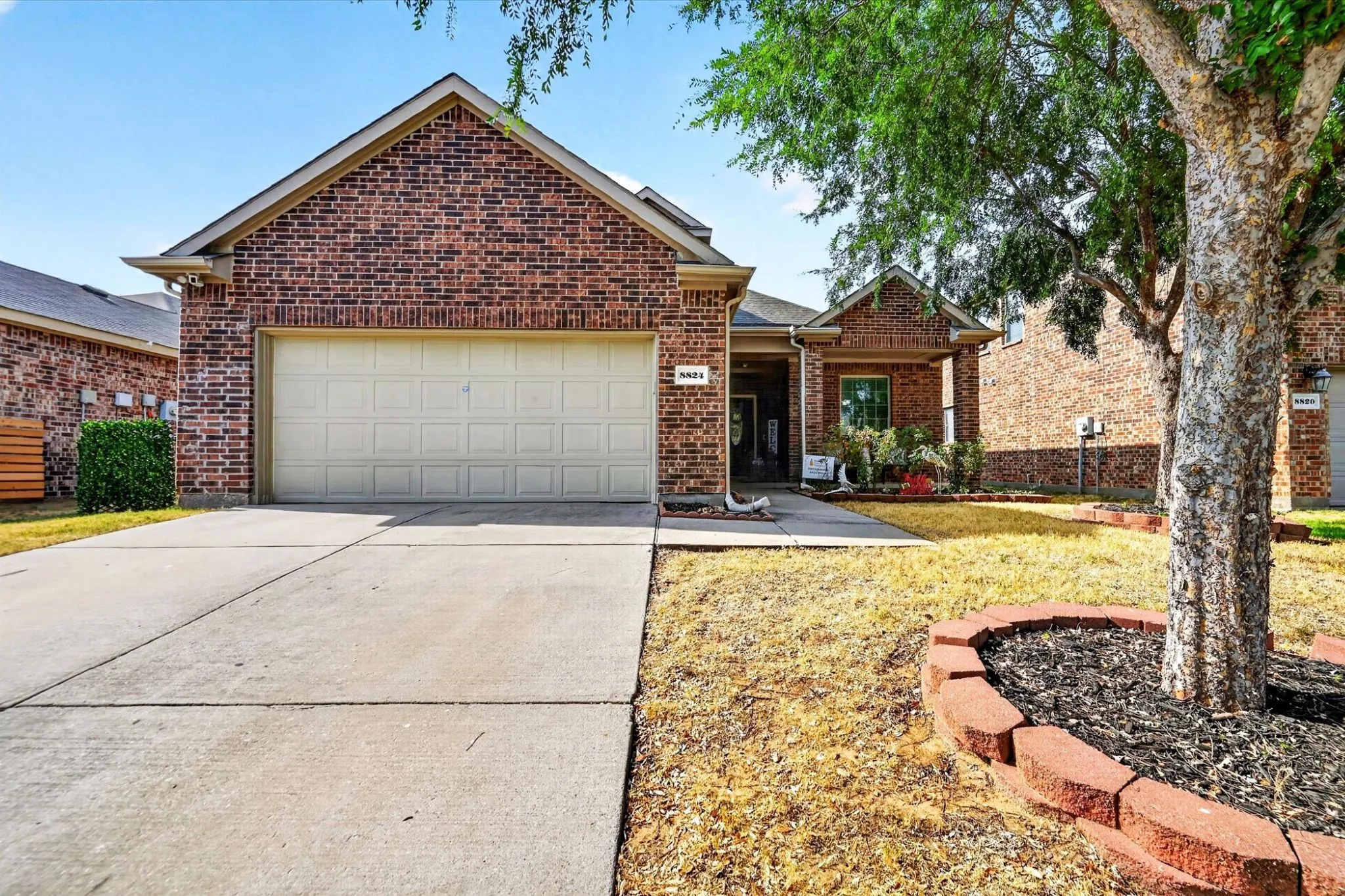 Brick exterior with a covered entry, attached garage, and concrete driveway