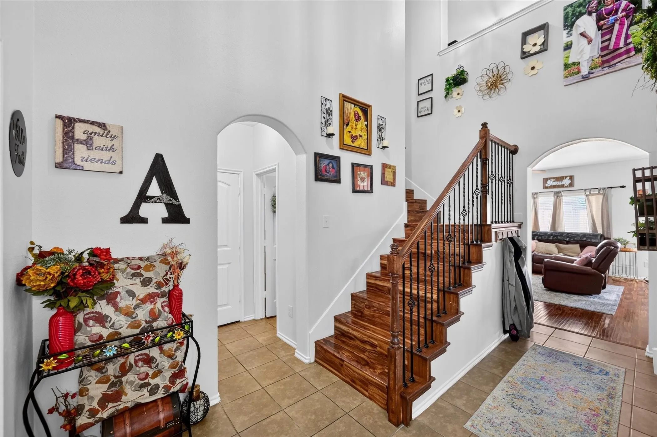 Grand entry with a tall ceiling, a wood-finish staircase with wrought iron balusters, and tile flooring