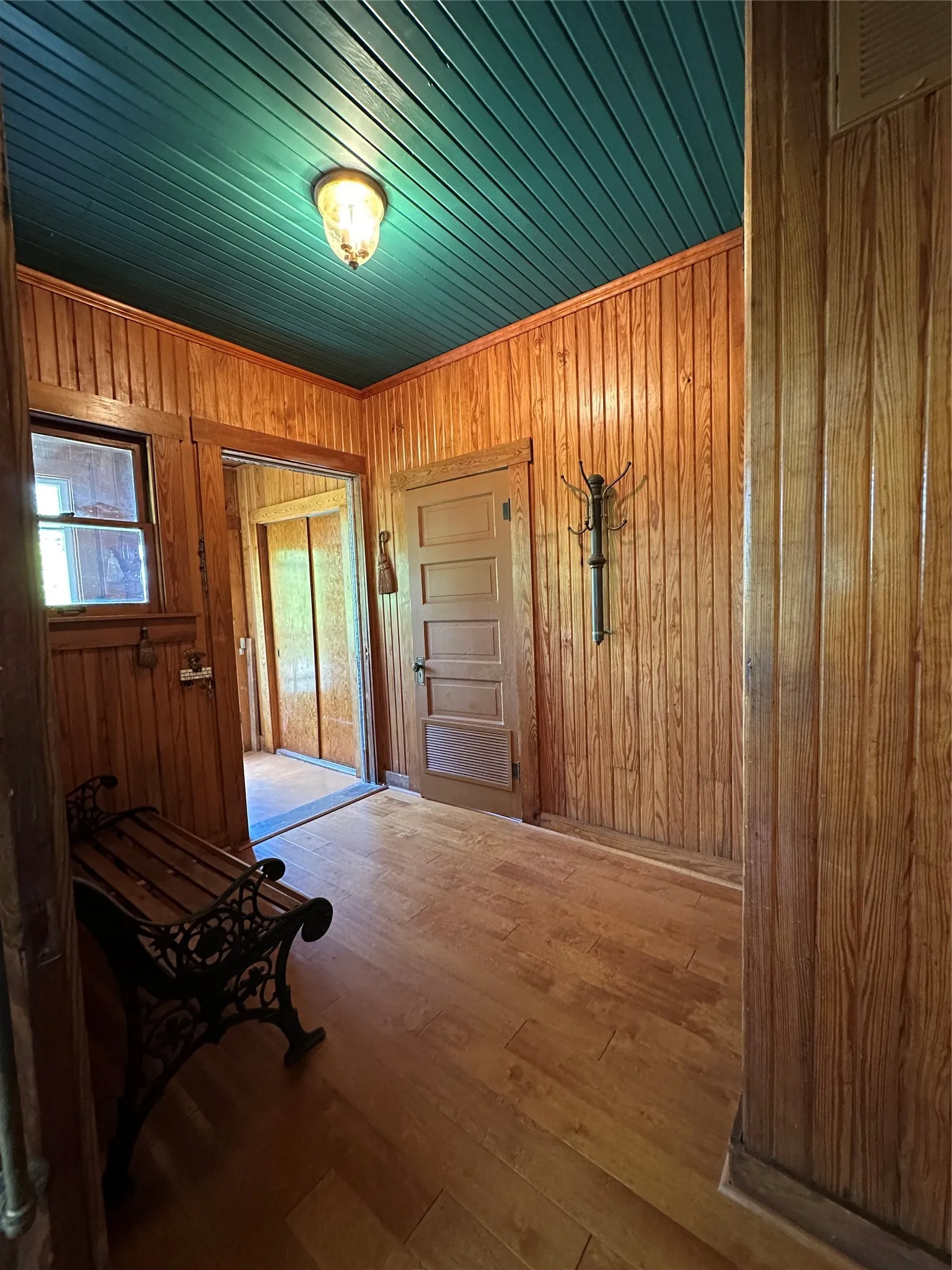 Wood-paneled walls and wood-finish flooring with a contrasting teal plank ceiling