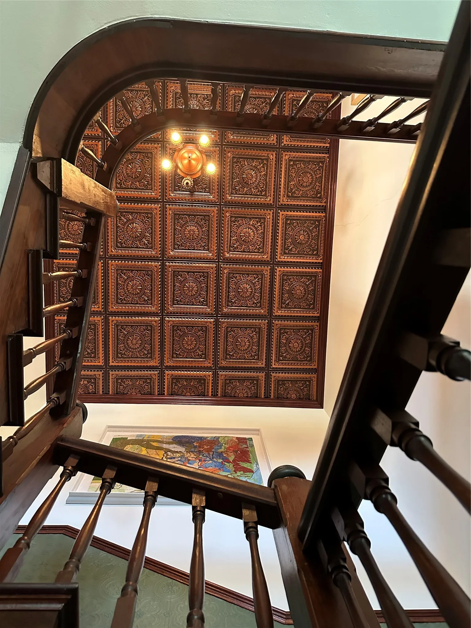 Ornate ceiling panels, wood staircase with turned balusters, and a decorative ceiling light fixture