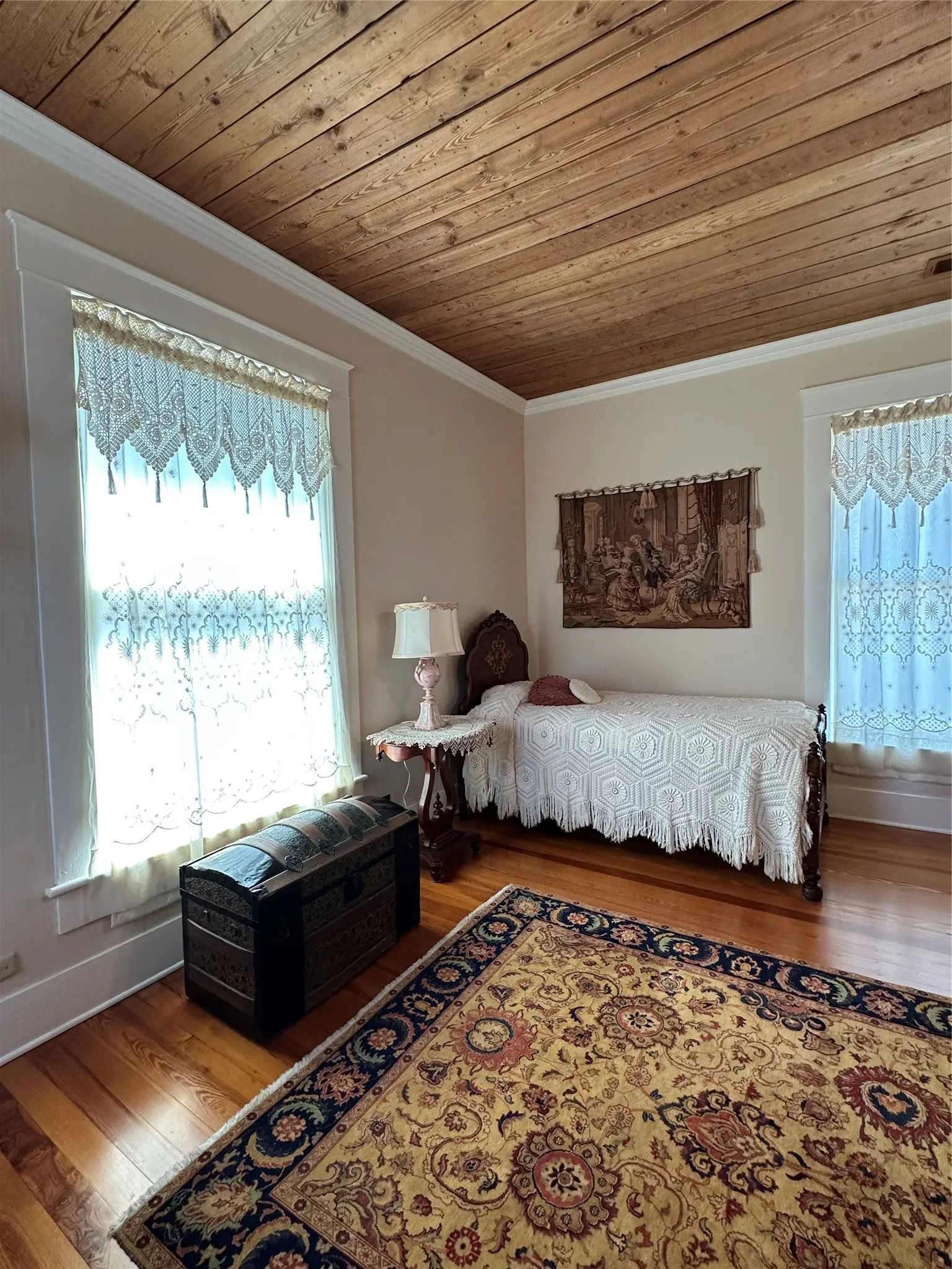 Wood-paneled ceiling with crown molding, hardwood flooring, and light-colored wall finishes