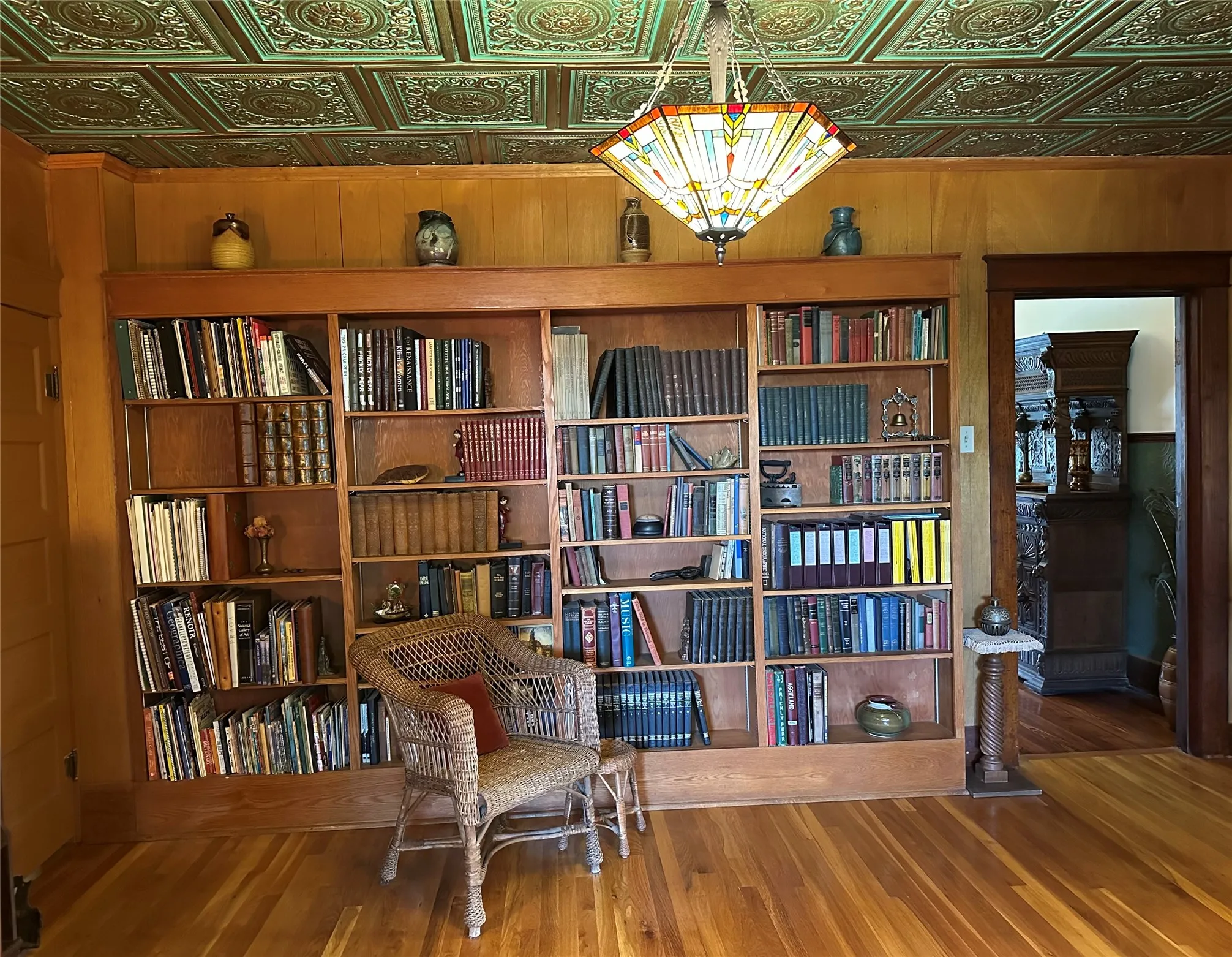 Built-in shelving, wood-finish flooring, and a decorative ceiling with a stained-glass style light fixture
