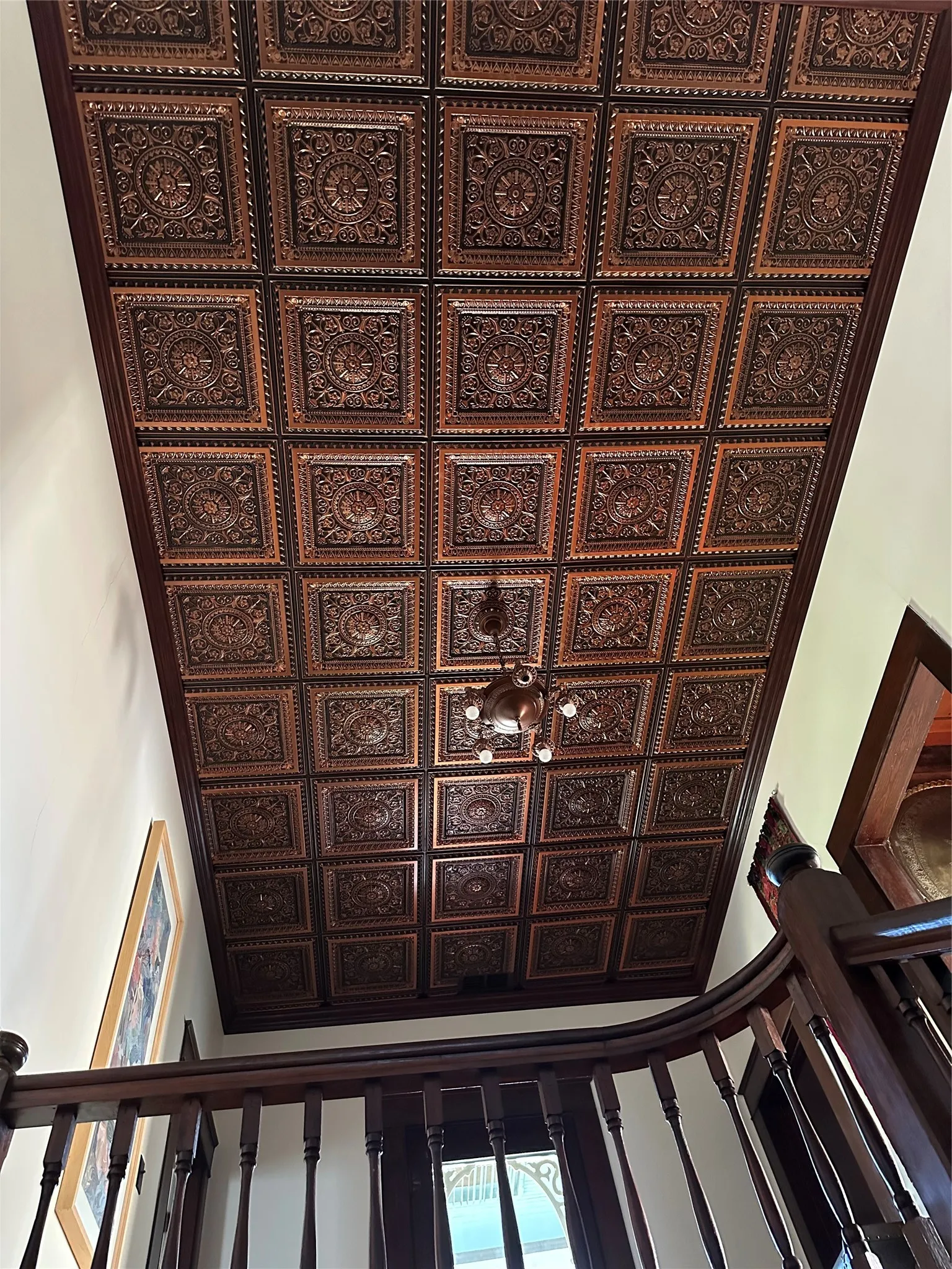 Coffered ceiling with decorative square panels, wood-finish trim, and central chandelier