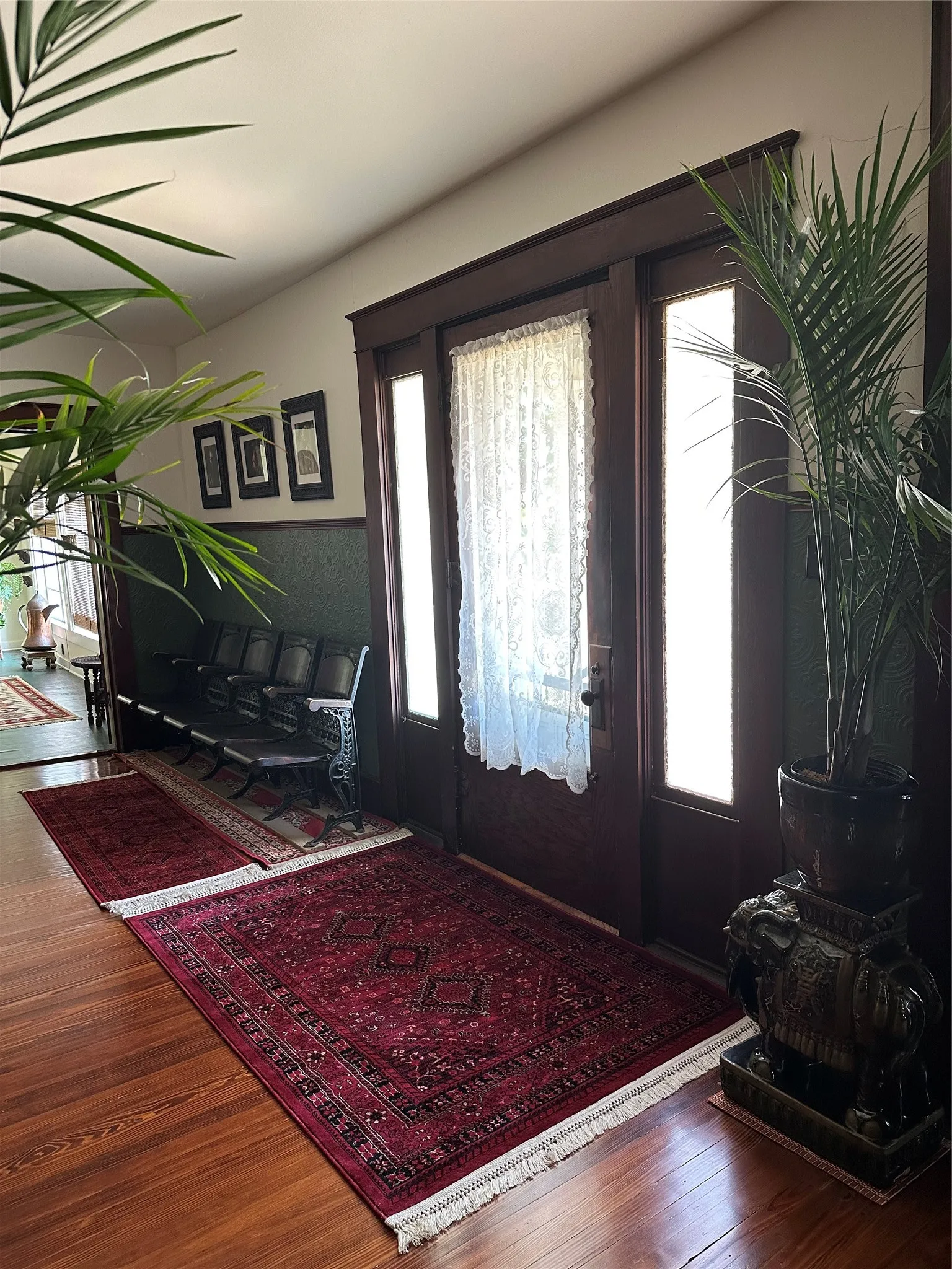 Hardwood flooring, dark wood trim, transom windows, and a paneled entry door