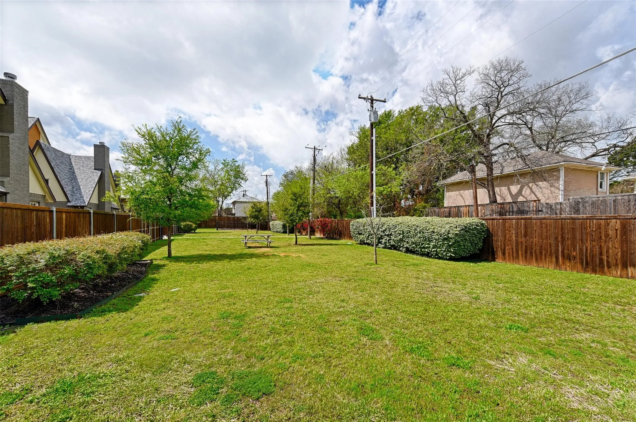 Expansive green space featuring a lush lawn, mature trees, and privacy fencing