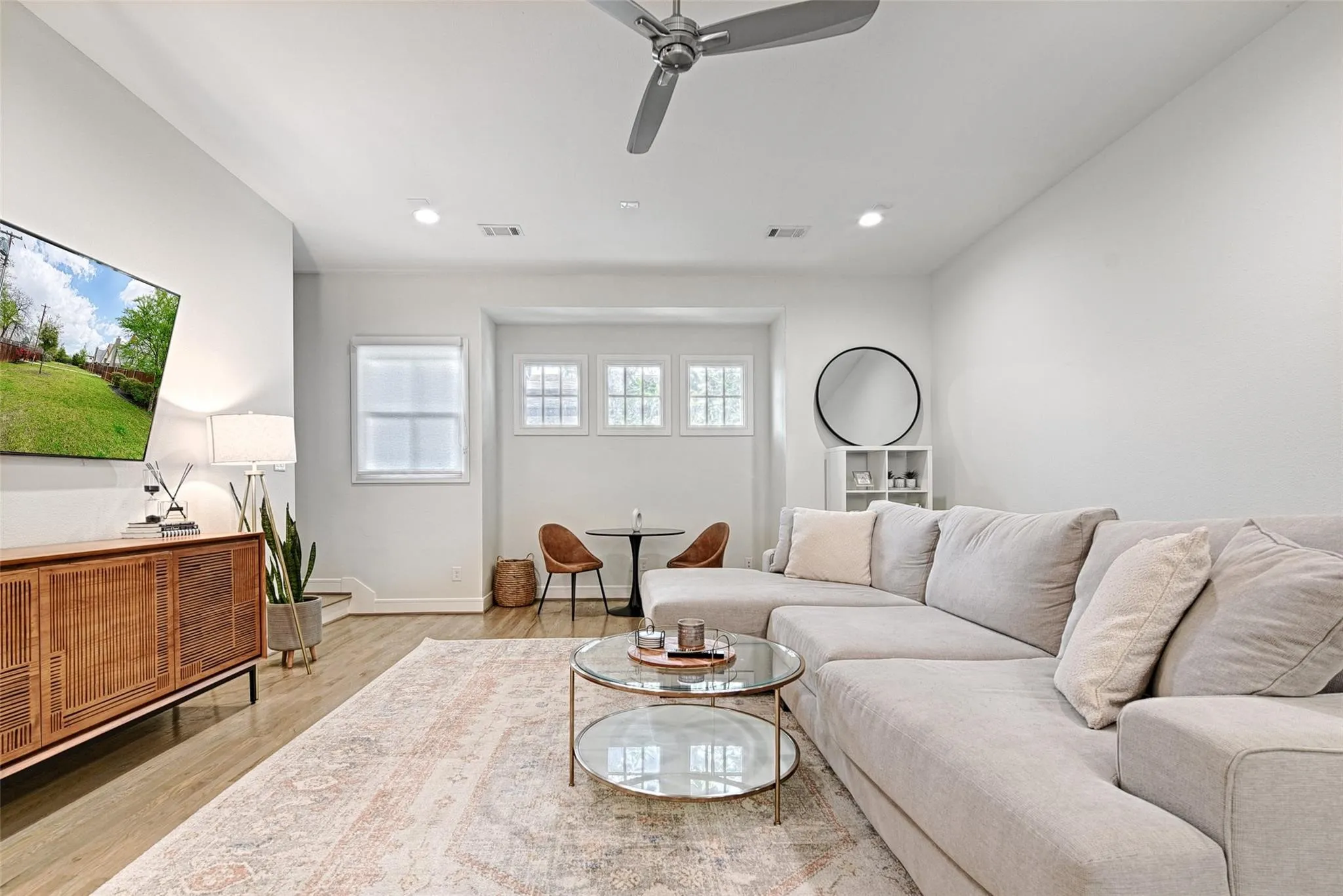 Wood-finish flooring with recessed lighting, high ceilings, and a ceiling fan