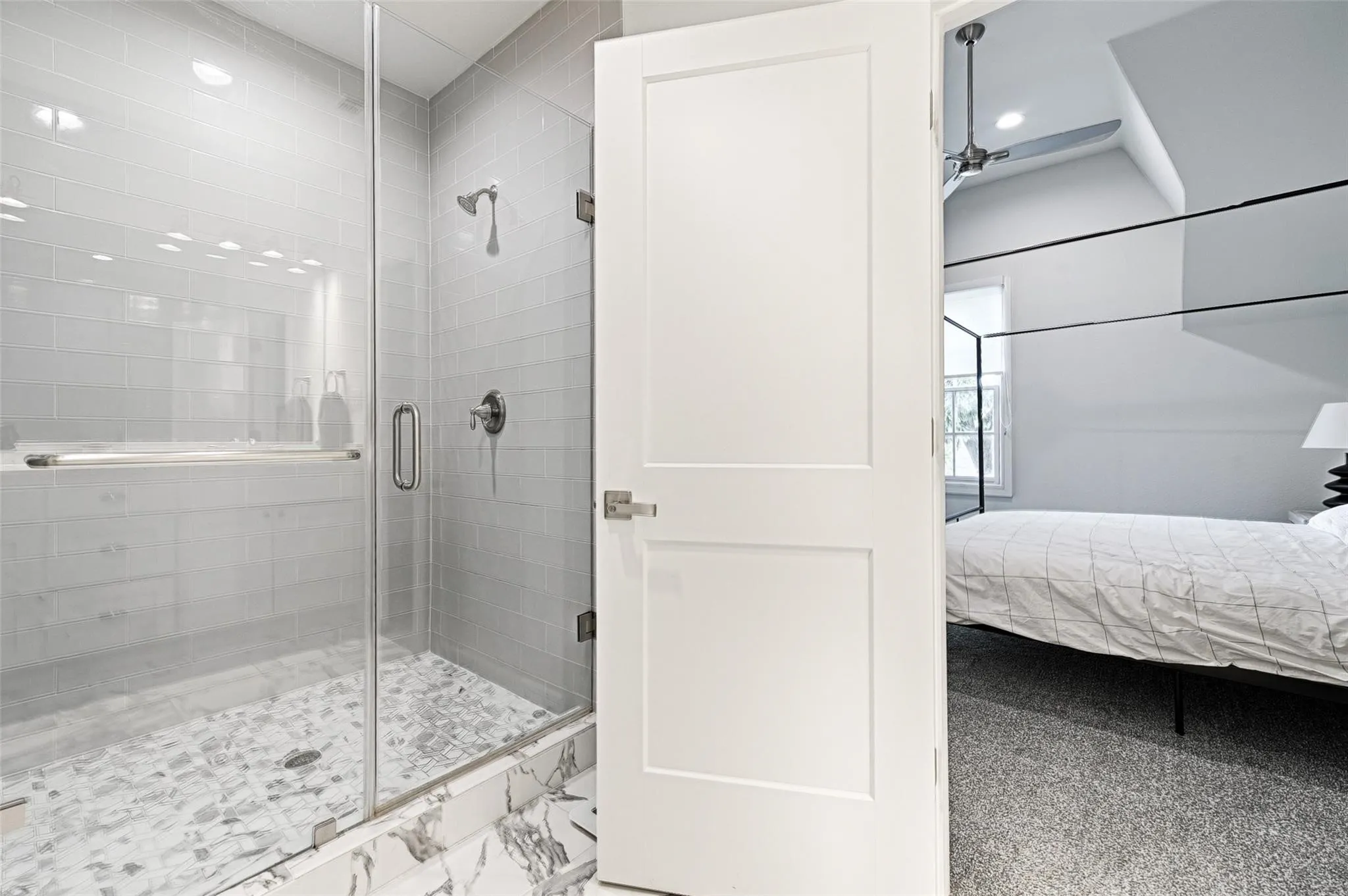 Glass-enclosed shower with subway tile surround, pebble tile shower floor, and a built-in shower niche